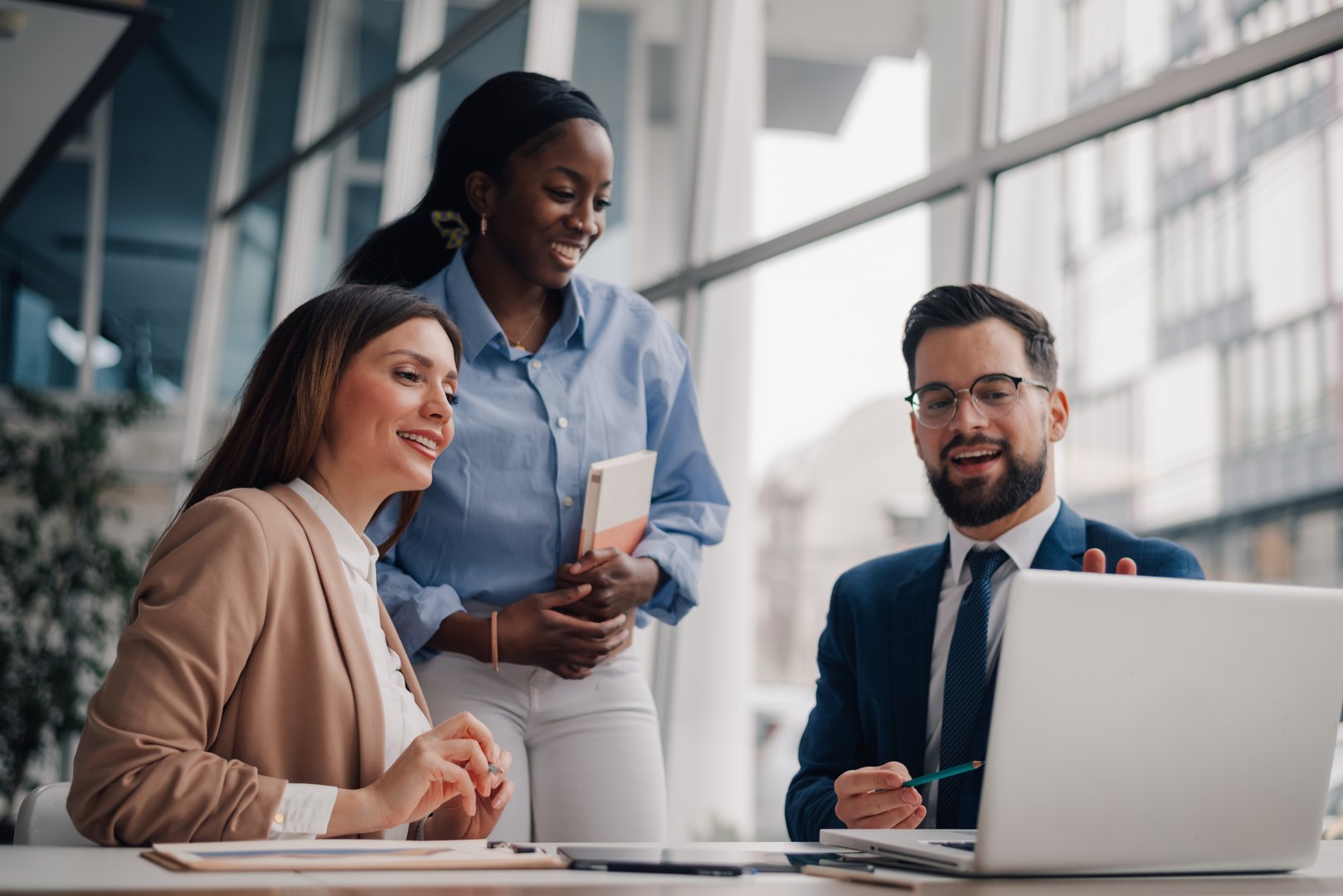 Diverse businesspeople collaborating on a project, using a laptop in a modern office environment