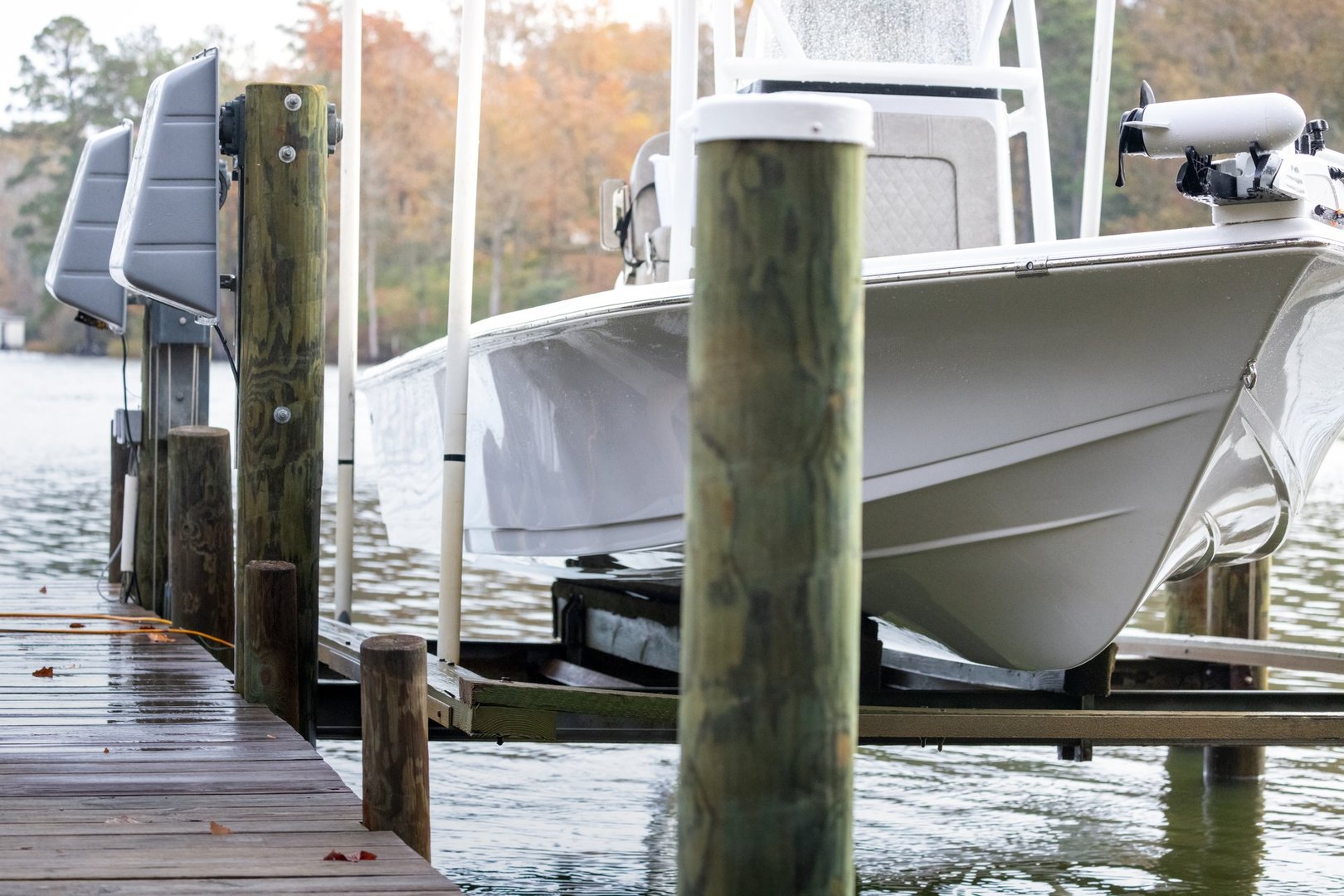 A wood dock with a wire and pulley elevator boat lift bolted to pilings on the Chesapeake Bay in Virginia