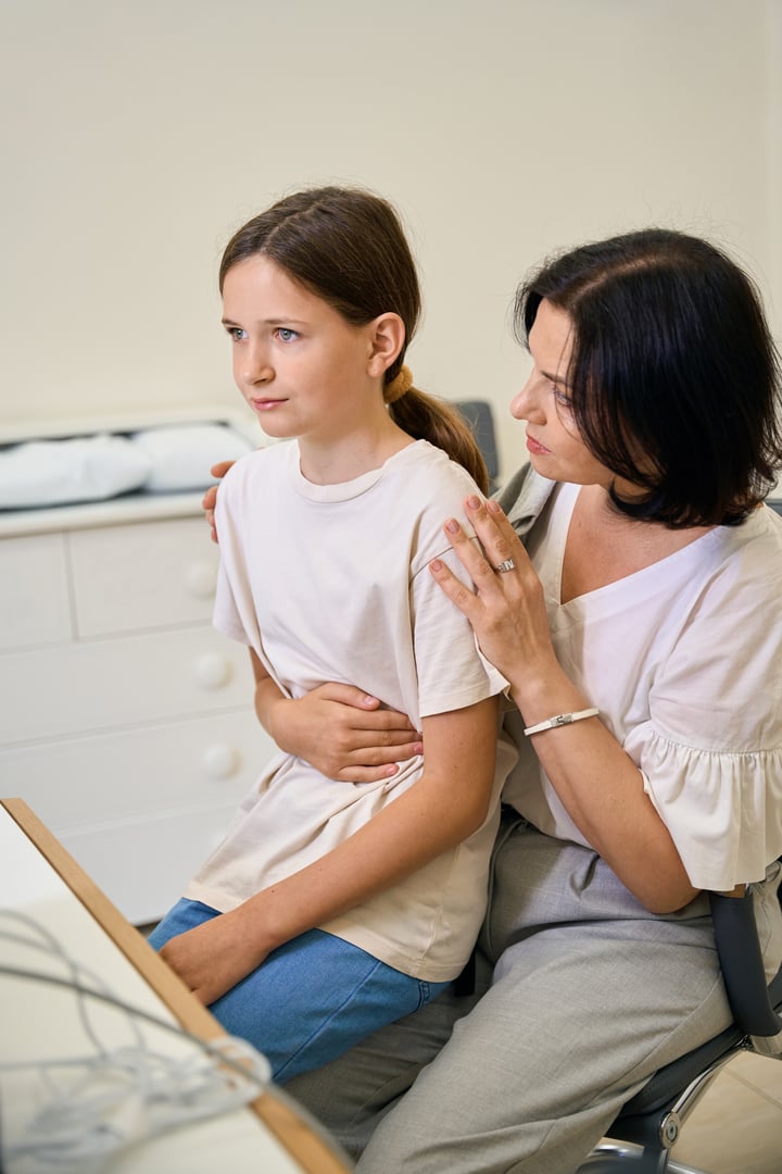 Child with his mother at an appointment with the family doctor, the girl complains of abdominal pain