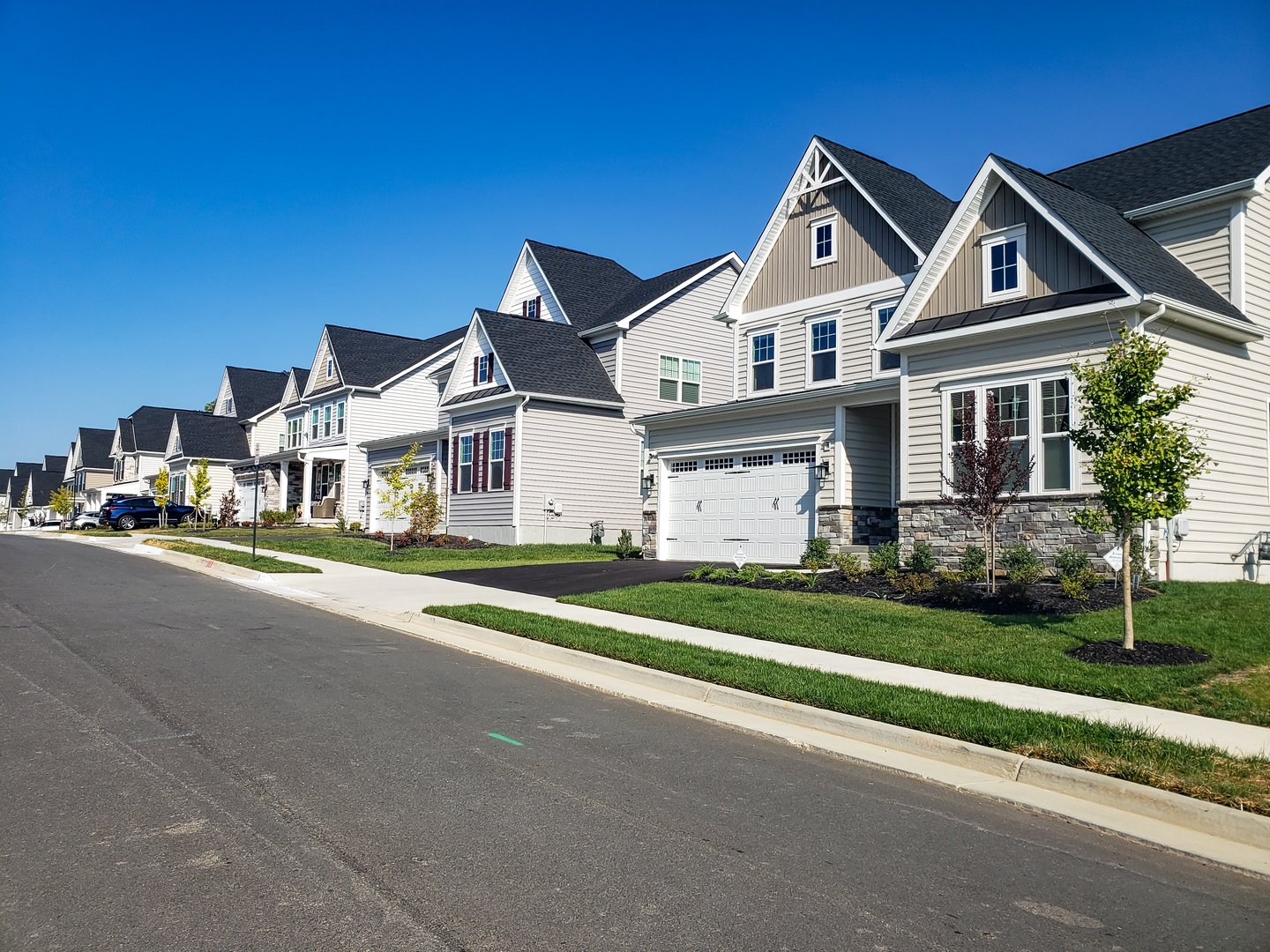 Picturesque street view with modern homes under blue skies. A row of modern detached homes.