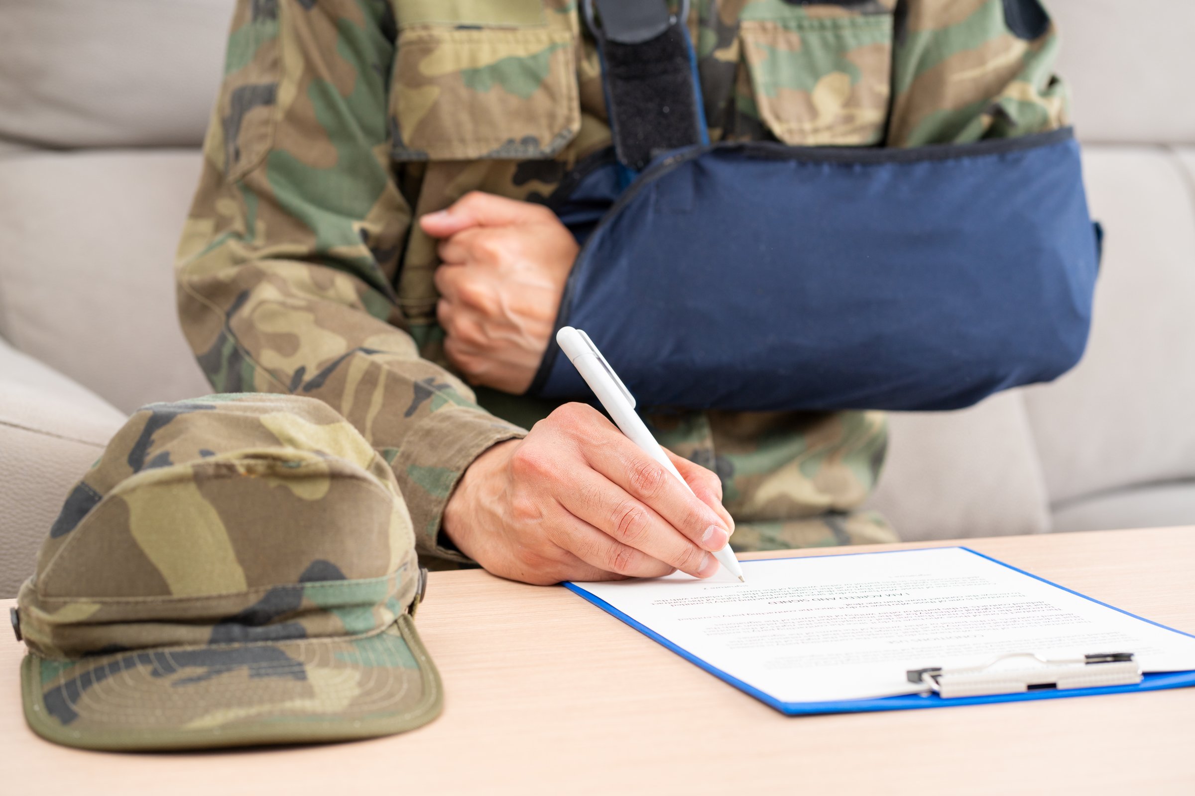 Front view of a handicapped soldier with sling signing contract at office