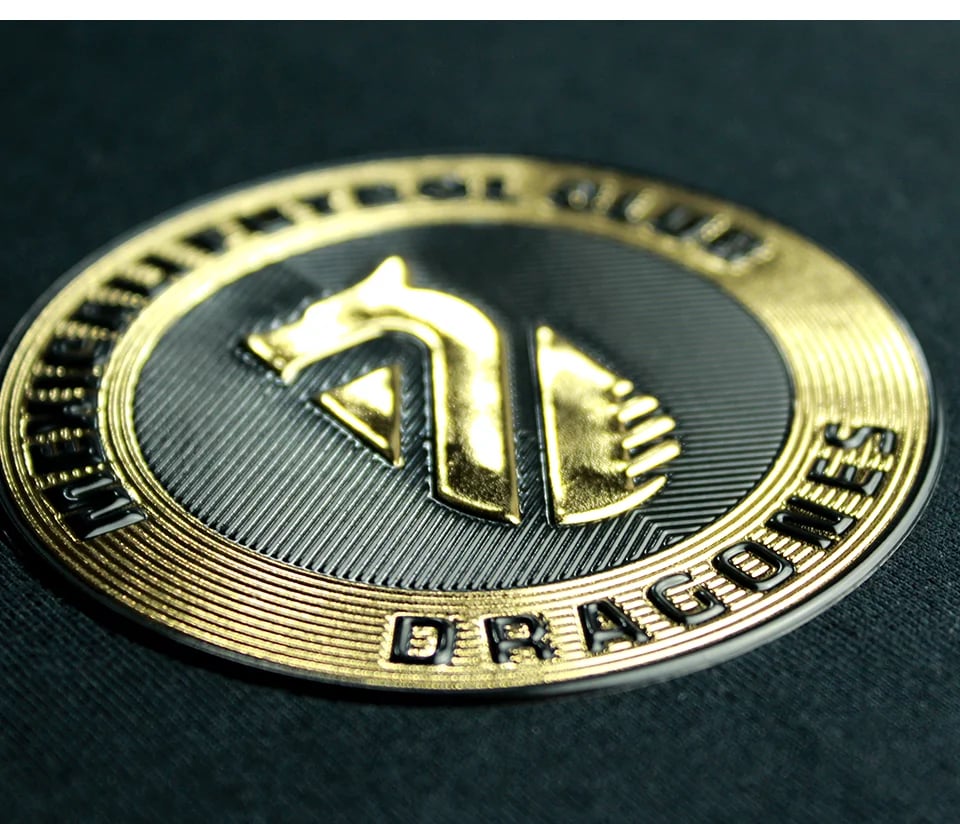 Metallic dragon-themed poker chip or medallion with embossed logos and text on a dark background.