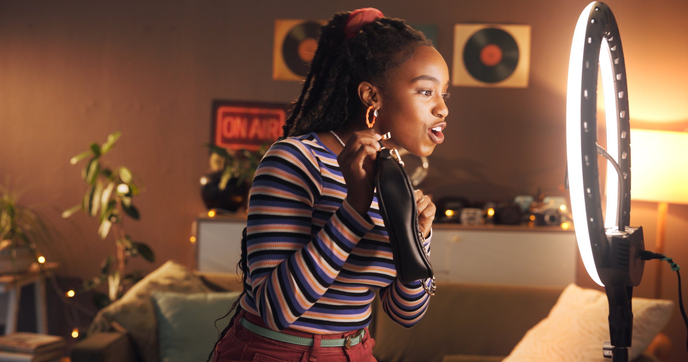 Home, influencer and woman with product review, live stream and promo for fans on website or online. Content creation, brand ambassador and black person with bag for sponsorship, ring light and night