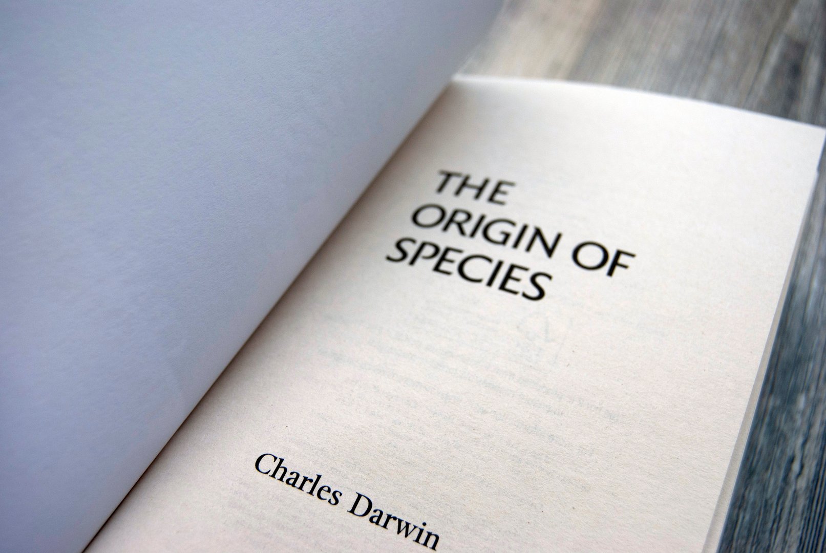 Charles Darwin's book 'The Origin of Species' on a wooden surface.
