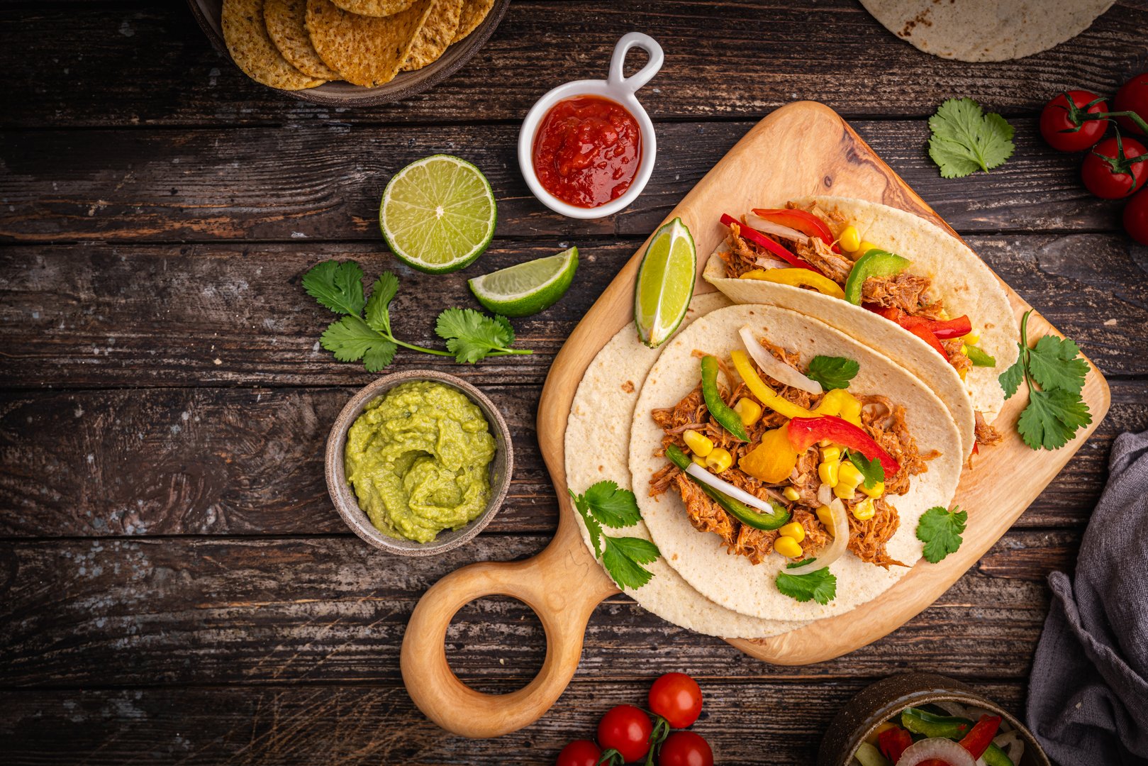 Healthy typical Mexican tacos with meat and vegetables, served with tortillas, salsa and sour cream on wooden background, top view. High quality photo