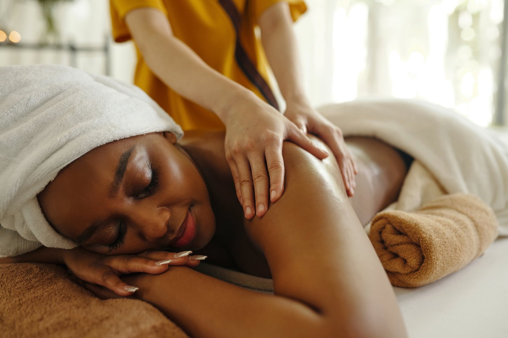 Woman enjoying relaxing therapeutic massage session on soft massage table. Therapist gently working on back muscles creating calming and serene atmosphere for relaxation