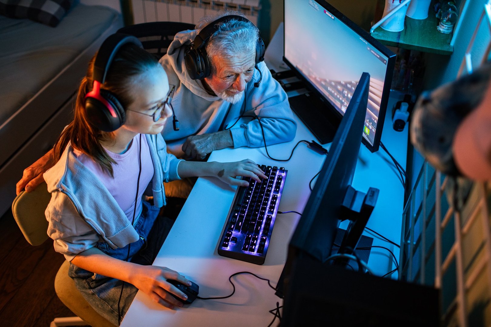 Close up of a Granddaughter and grandfather playing video games on a pc in the bedroom