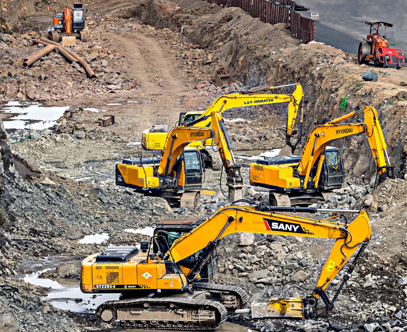 Pune, Maharashtra, India- September 24th, 2021: Excavators of various companies digging simultaneously for road widening work.
