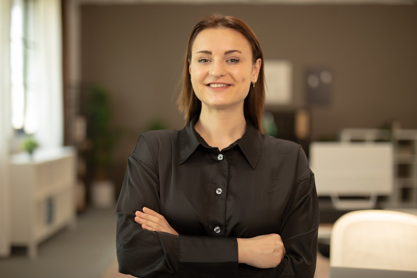 Portrait of a young businesswoman smiling with arms crossed in the office