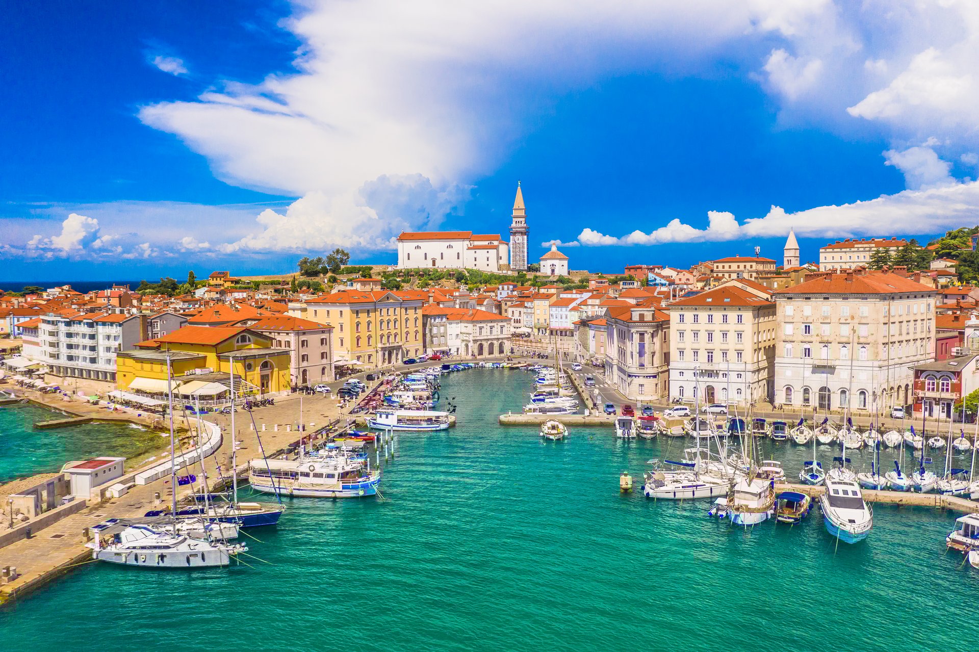 A breathtaking aerial view of Piran, Slovenia, showcasing its charming harbor, colorful Venetian-style buildings, and the town center along the Adriatic coastline, capturing the essence of place