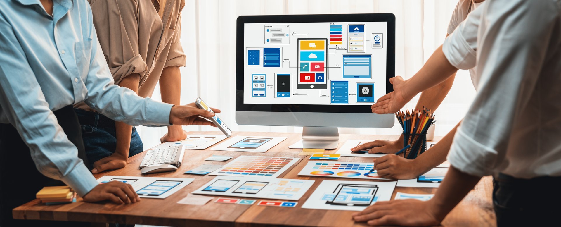 Panorama shot of front-end developer team brainstorming UI and UX designs for mobile app on laptop computer screen. User interface development team planning for user-friendly UI design. Scrutinize