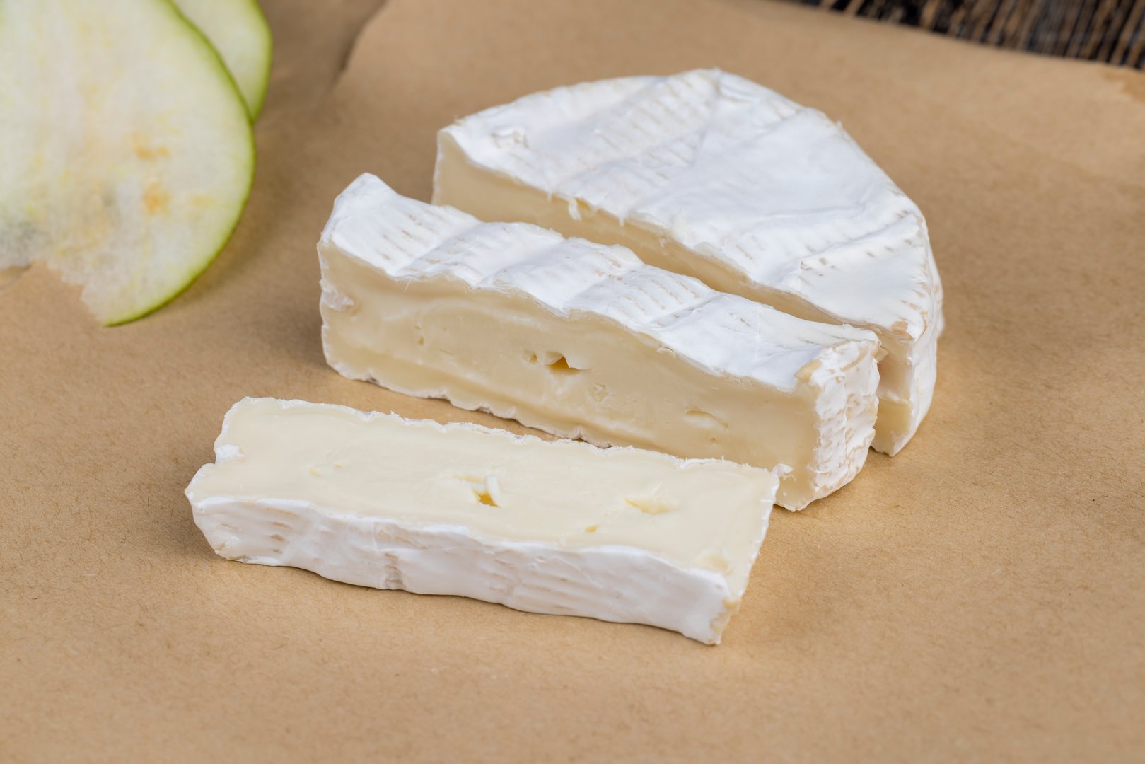 soft processed cheese with white mold on the table, sliced white cheese with mold close-up