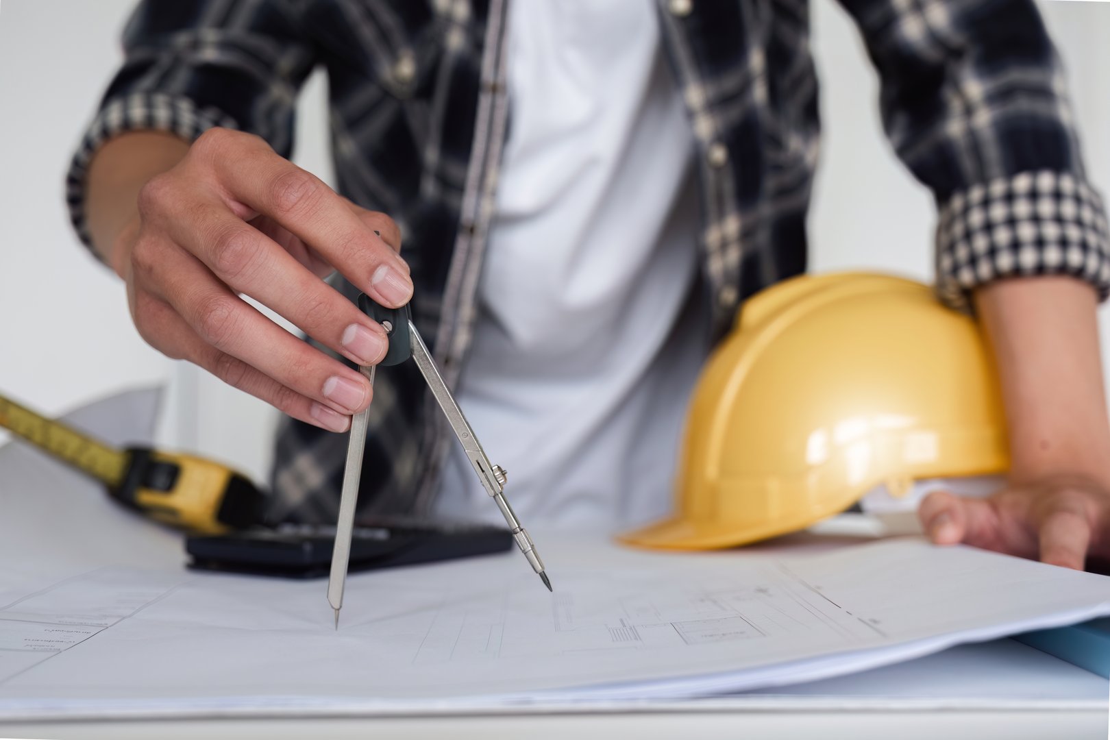 Young Asian engineer drawing construction project plans on plan paper on table in office.