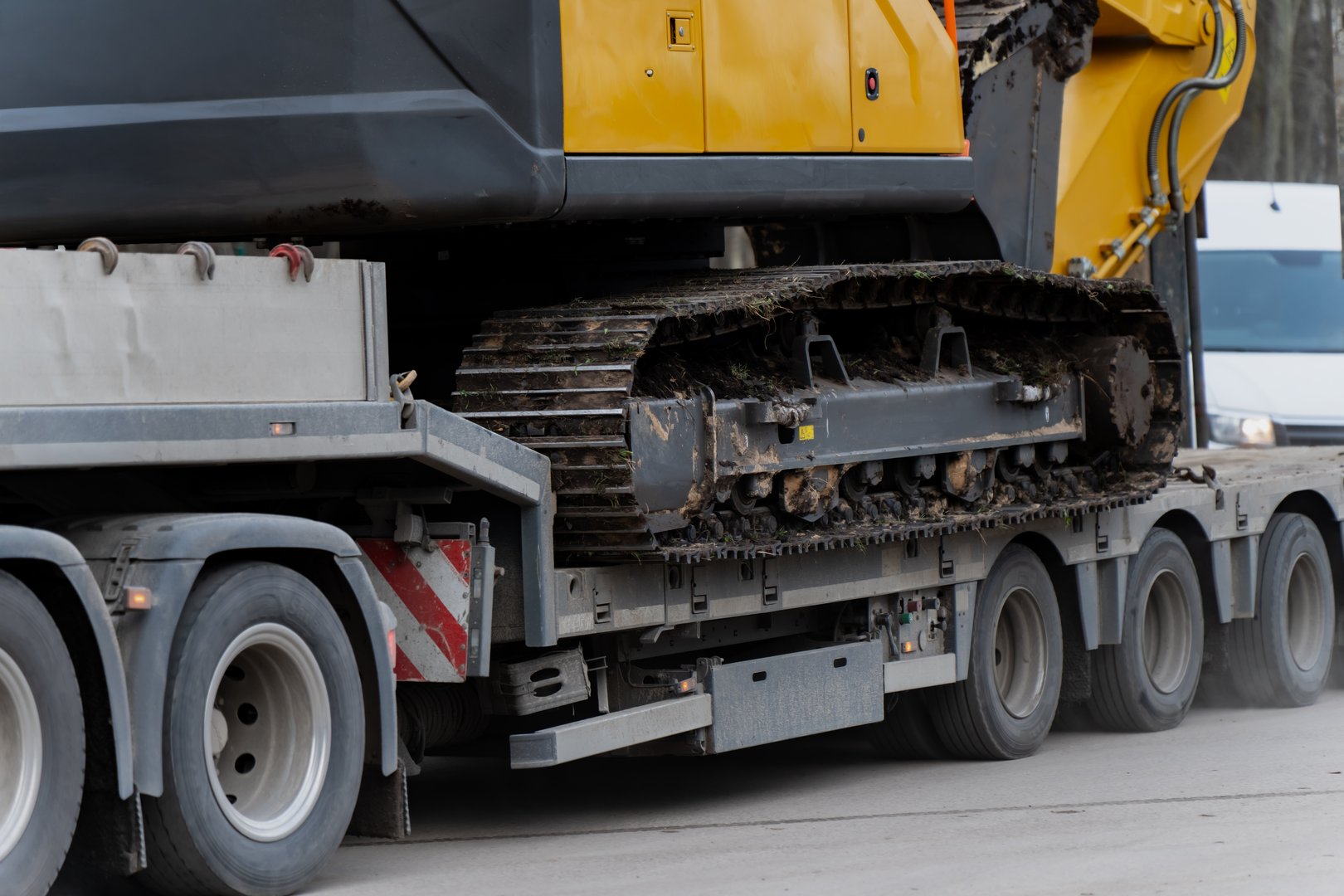 Tracked excavator crawler system positioned on multi axle lowbed trailer, illustrating heavy equipment transport with reinforced frame design and logistics operation