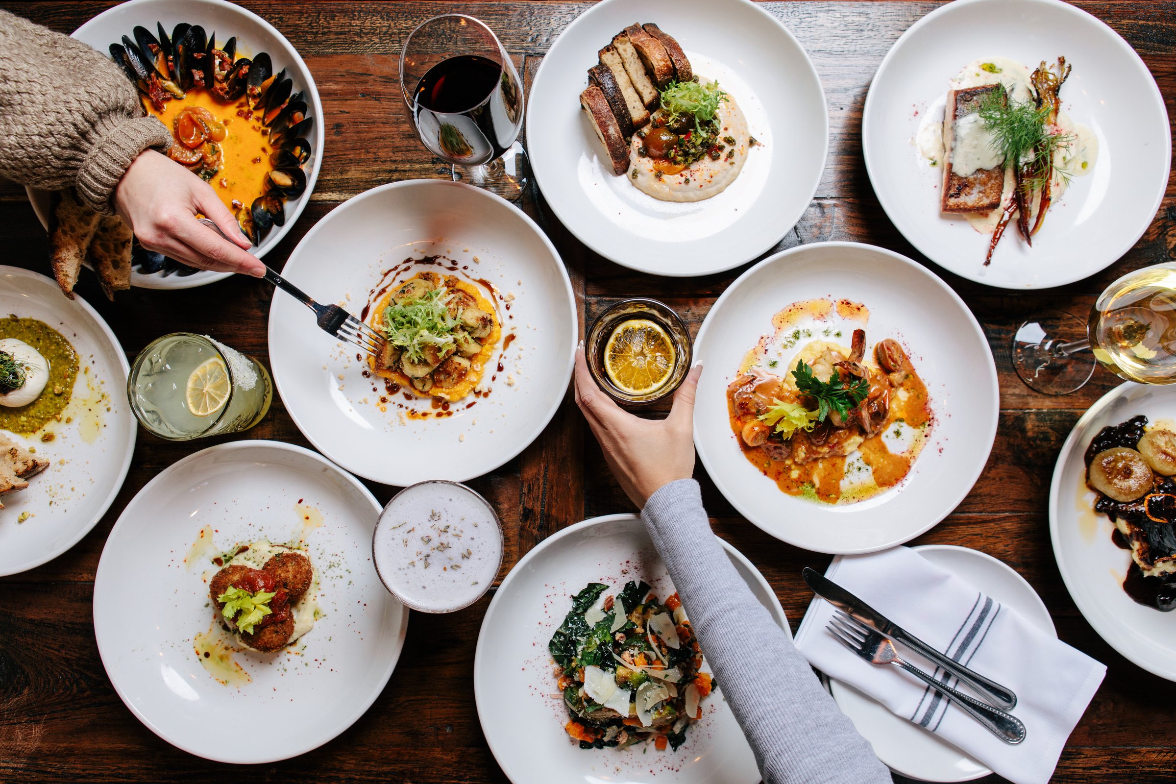 A bird's-eye view showcases a bountiful spread of delicious dishes and beverages on a rustic wooden table, ideal for food blogs, restaurant promotions, or lifestyle content.