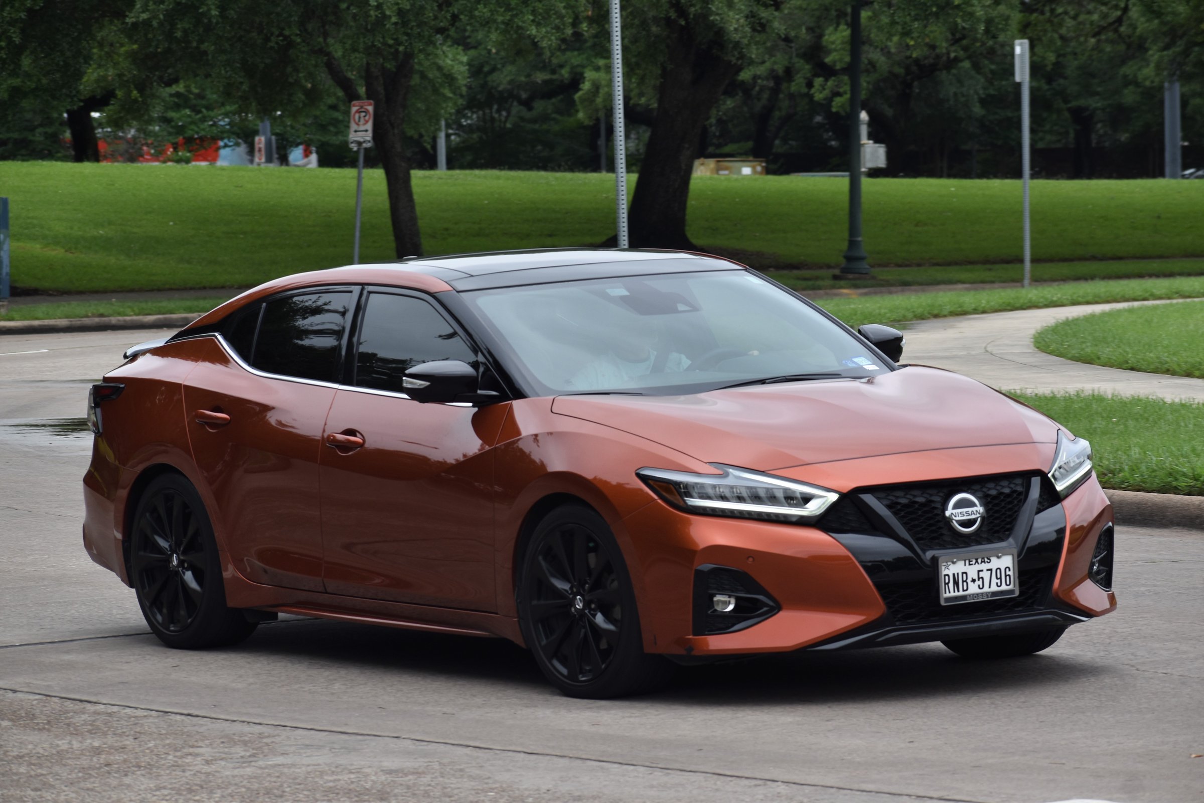 Houston, TX USA, April 29, 2024- An orange Nissan Sentra sedan driving on a road near a nature reserve.