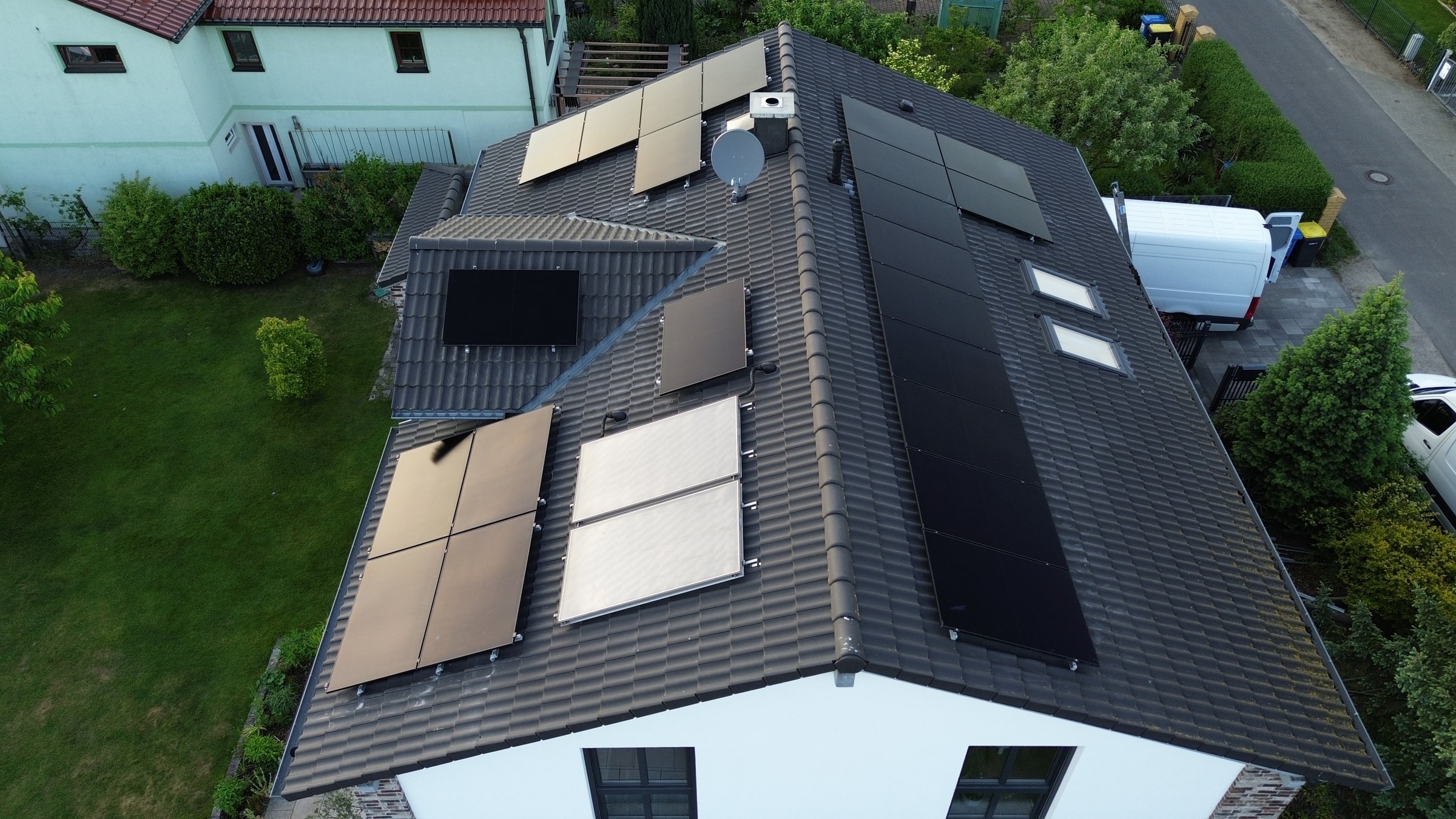 Roof of a house with multiple solar panels installed, surrounded by green lawns and neighboring homes.