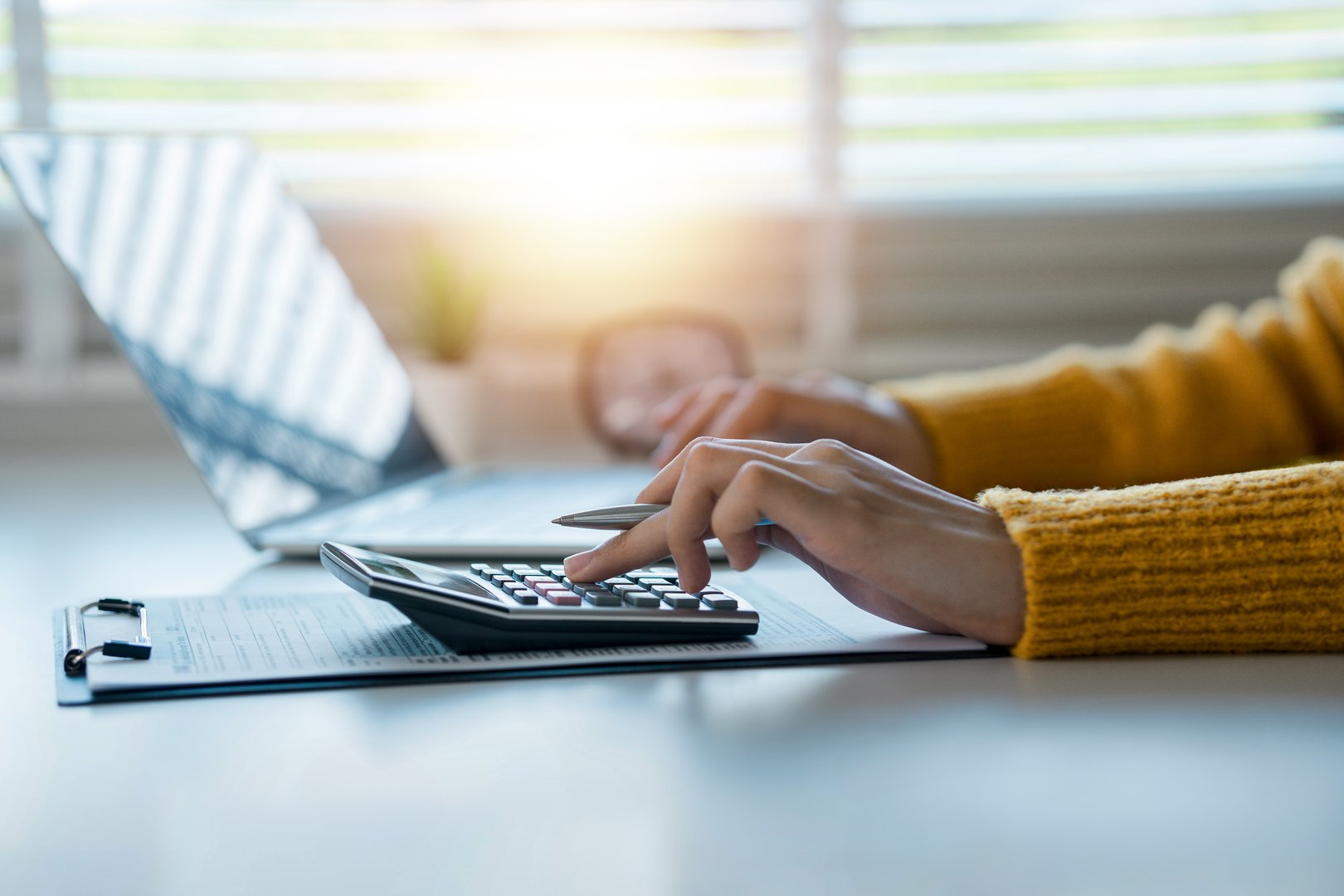 The concept of tax return preparation and financial management. Businessman calculates taxes using calculator and laptop. finance, Income tax,  tax documents, and savings