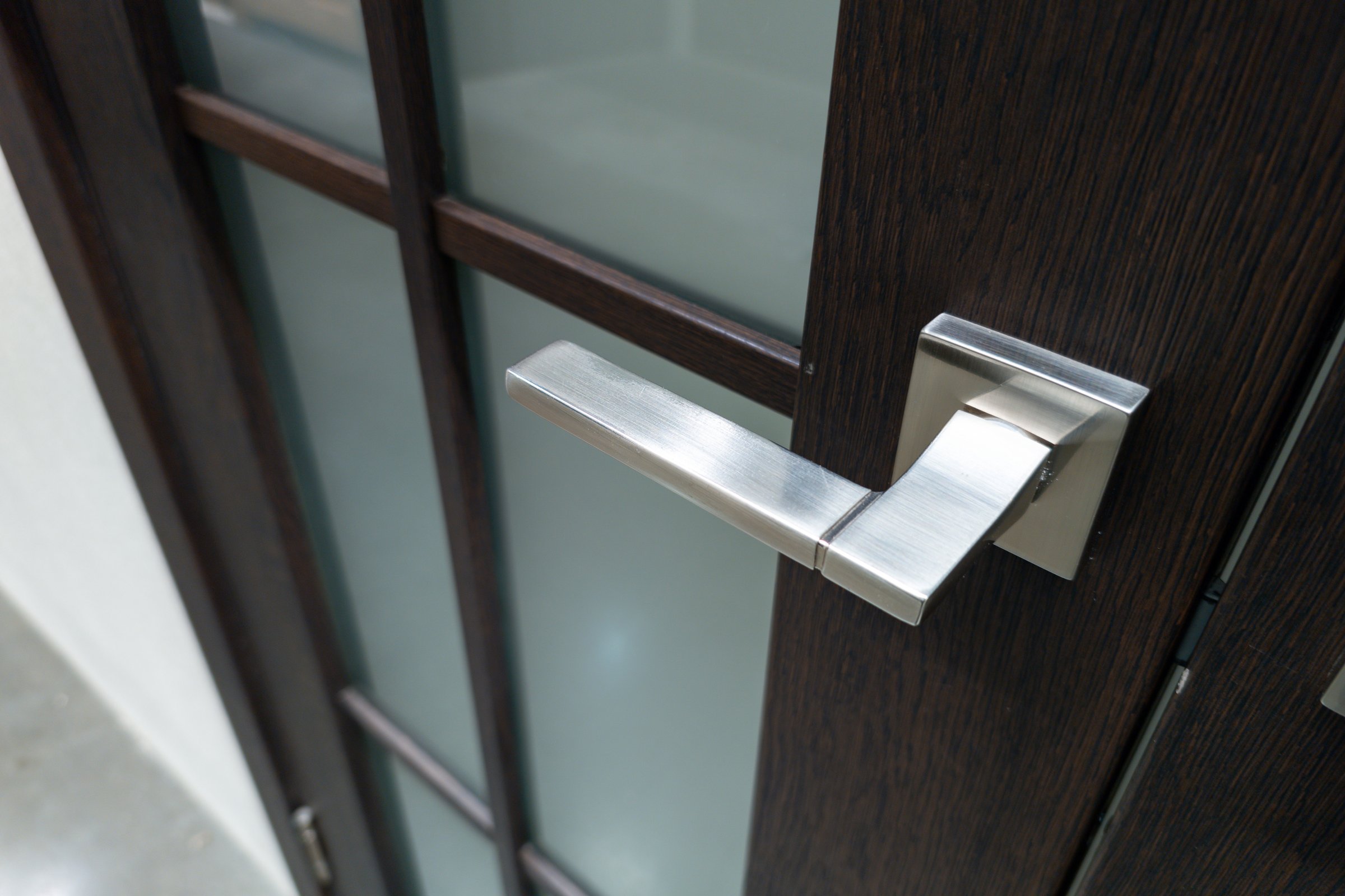 A stylish door handle with a brushed metal finish is mounted on a wooden door, showcasing a blend of elegance and modern design in a contemporary space.