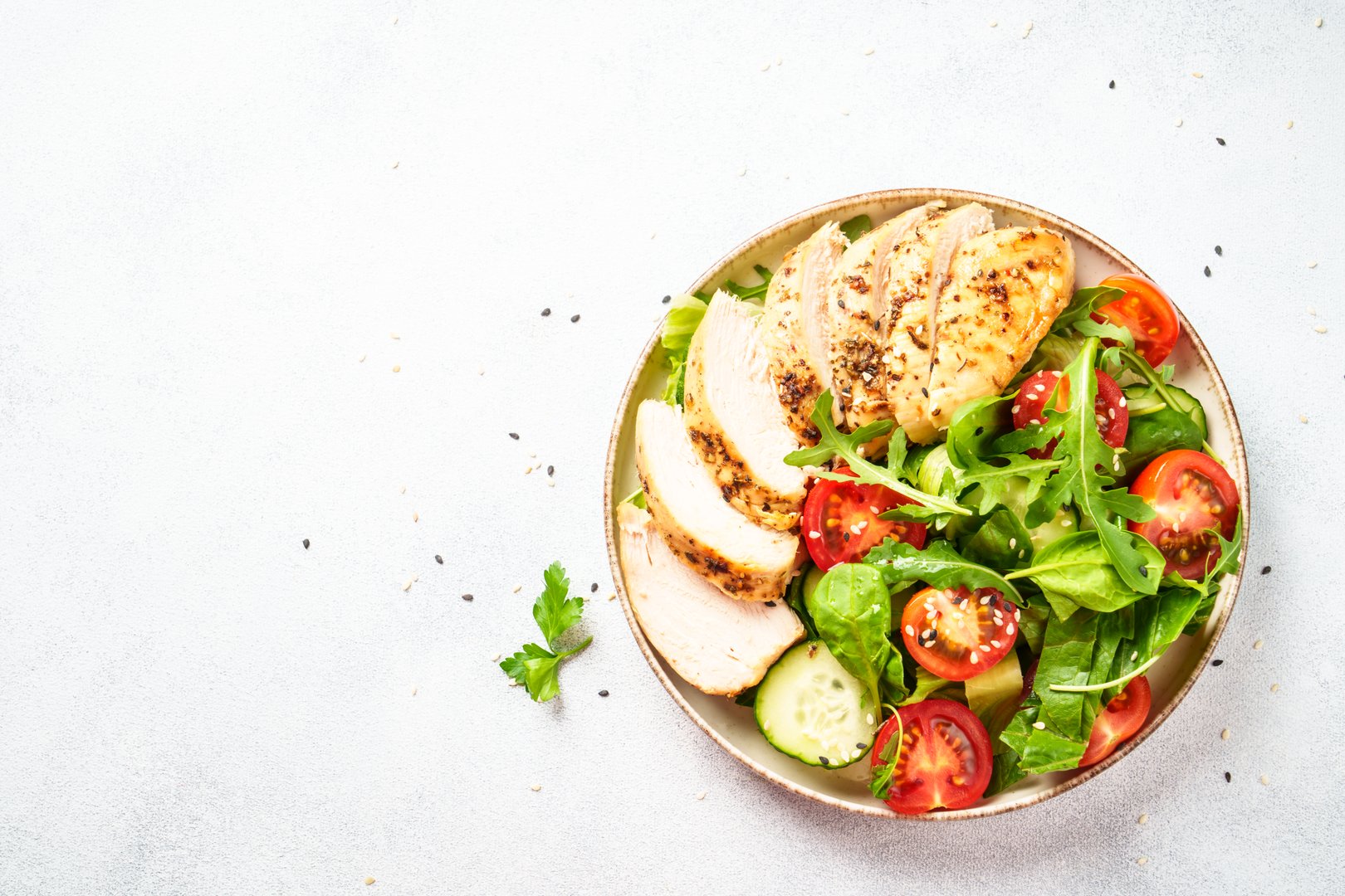 Chicken salad with grilled meat and vegetables at black table. Top view with copy space.