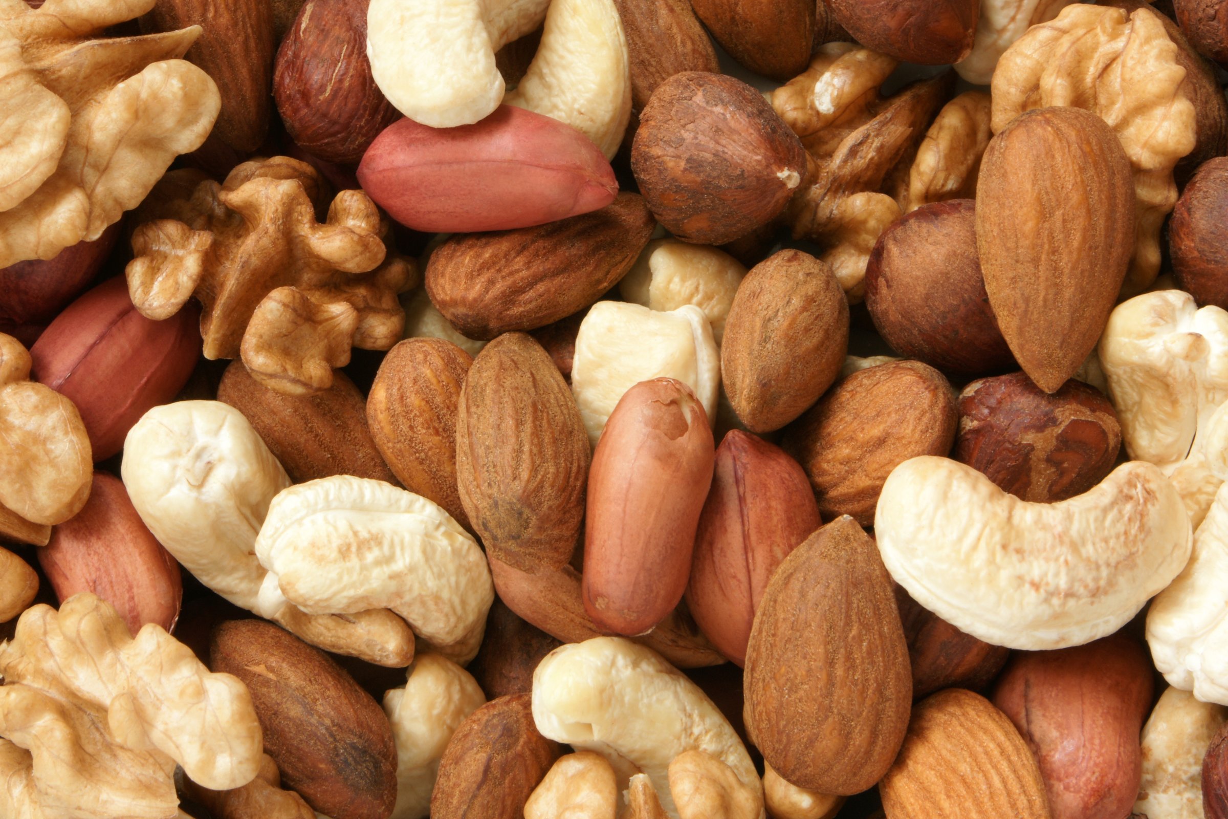 A variety of mixed nuts including walnuts, almonds, cashews, and peanuts, creating a textured, natural background.