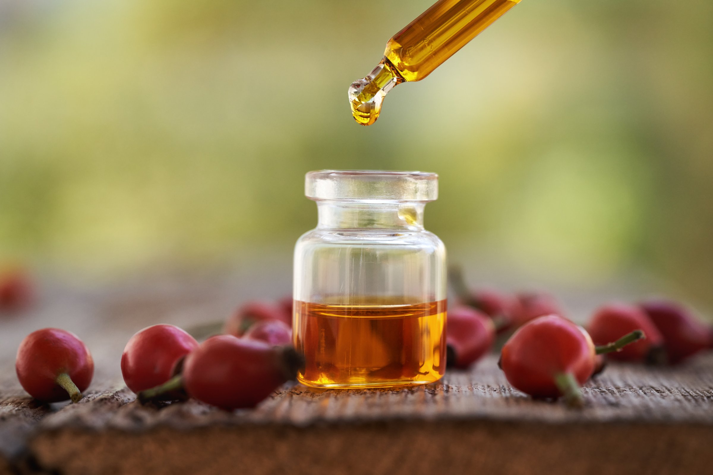 Dropping rose hip seed oil into a glass bottle outdoors