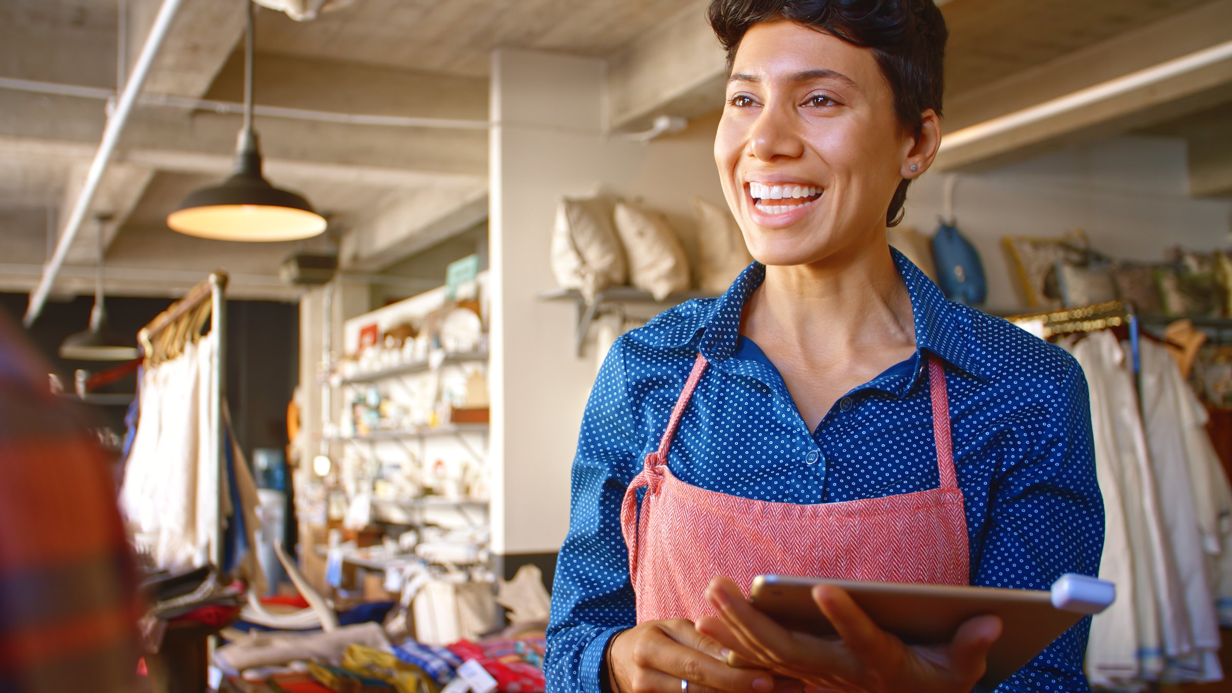 Close Up Of Female Sales Assistant With Digital Tablet Helping Customer In Gift Shop Or Store