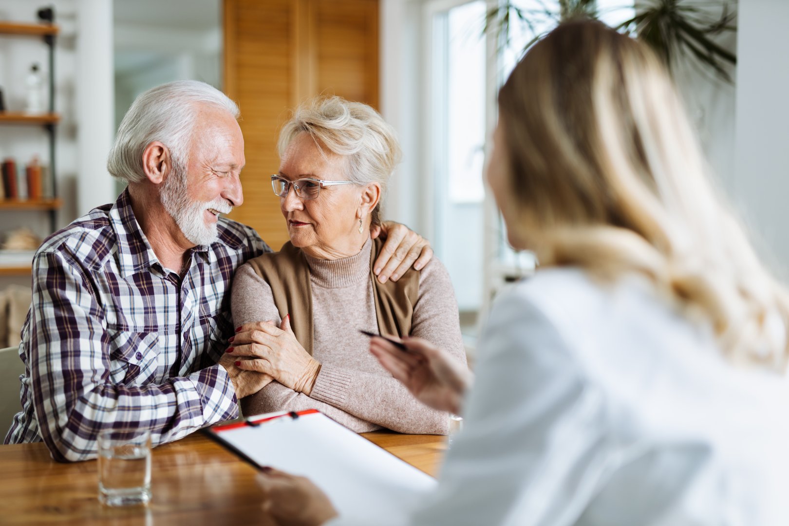 Happy mature couple talking to their doctor during her home visit
