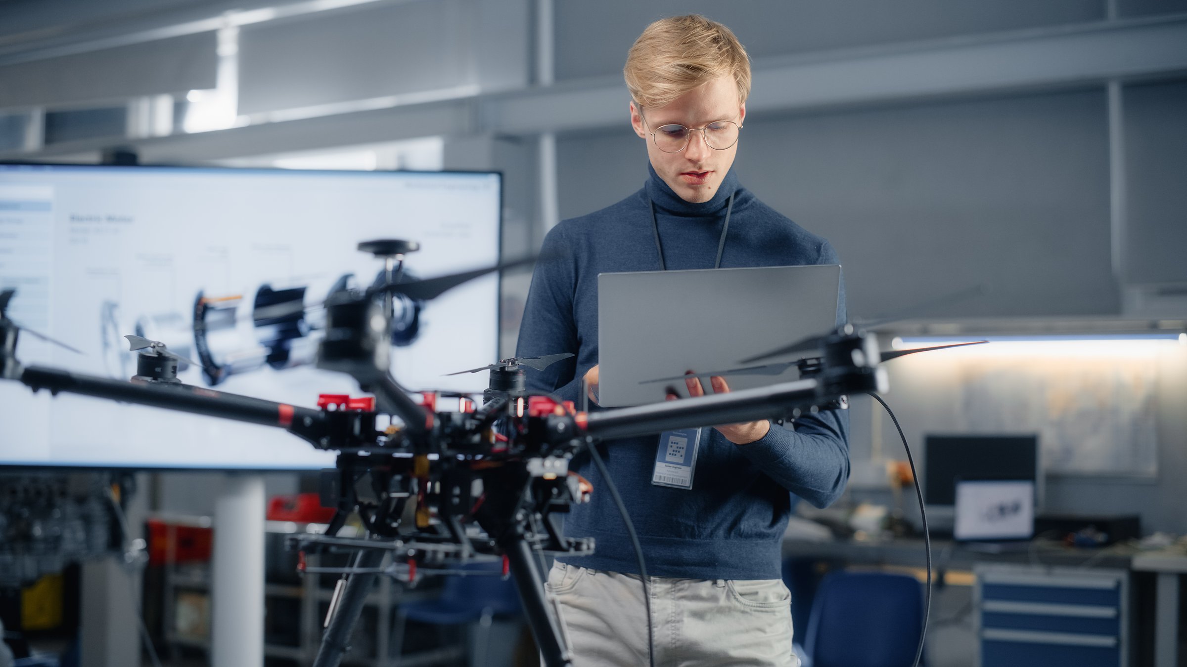 Young Male Developer Programming on Laptop Computer. Working on a New Drone Design in the Research Center Laboratory. People Creating Futuristic Unmanned Aerial Vehicle Concept.