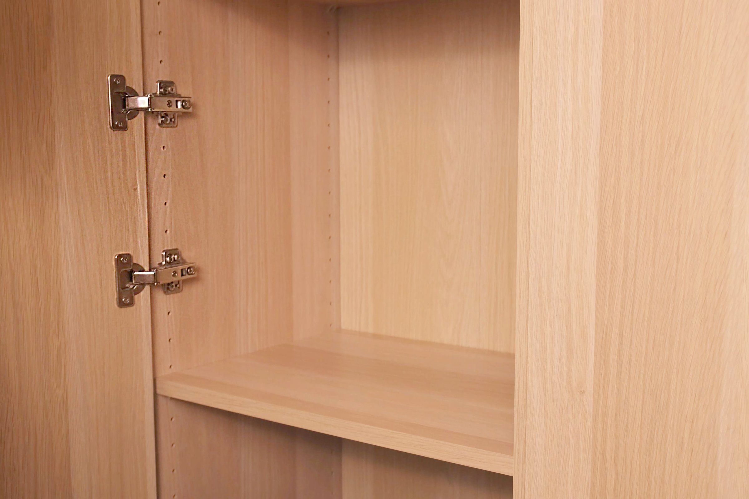 An empty wooden shelf inside a linen wardrobe awaits organization in a modern home interior showcasing available storage space and minimalist design