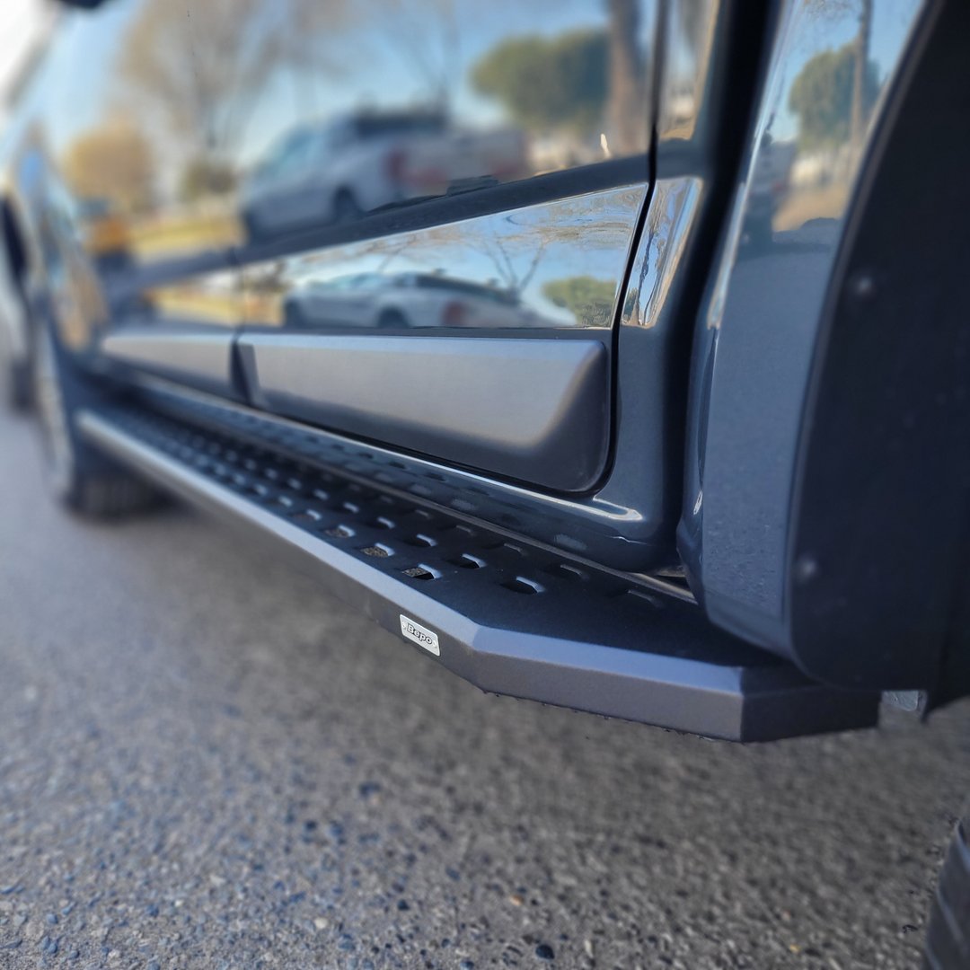 Close-up of a trucks black side step on a paved surface, with focus on the step and blurred background.