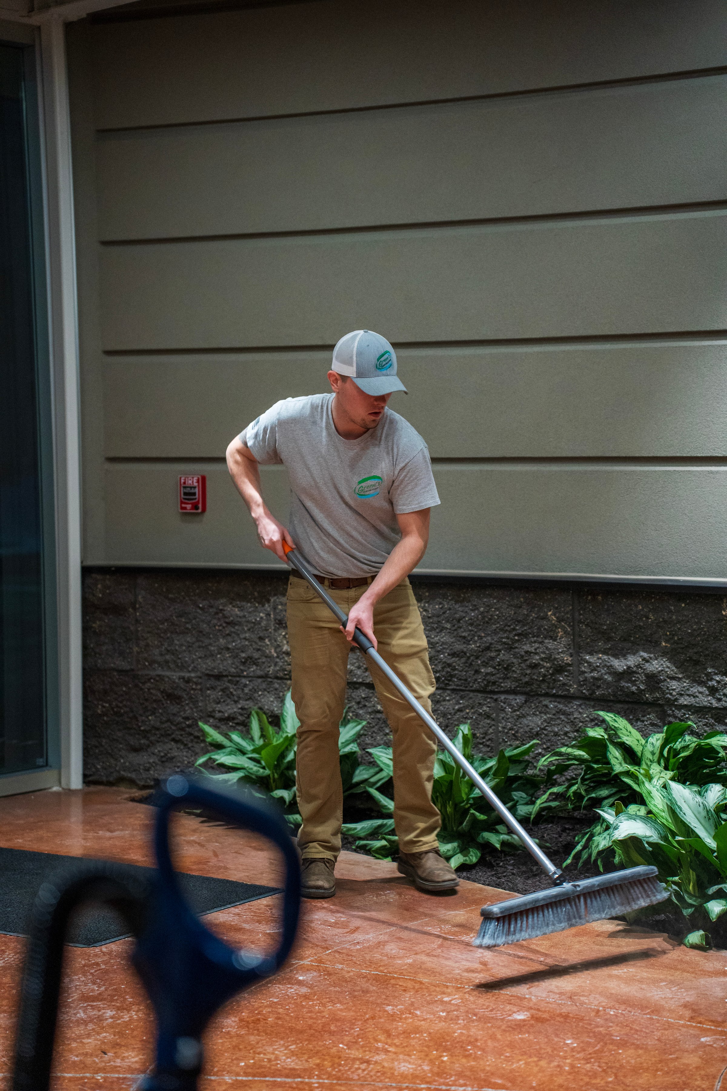 Professional cleaner in action wearing green uniform and yellow gloves