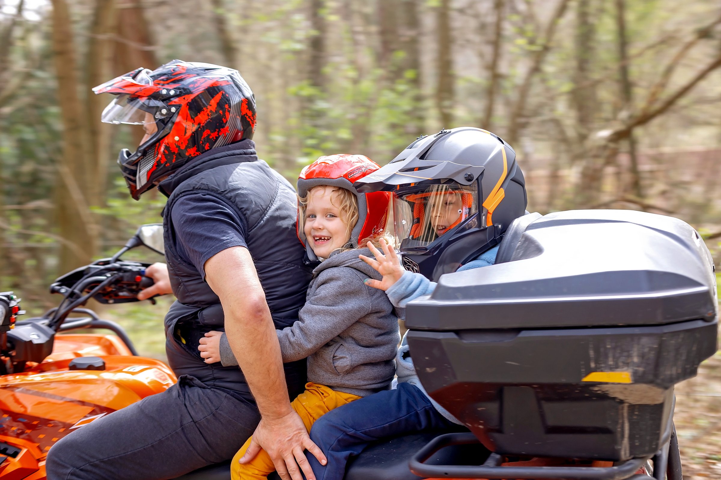 Children, riding on a buggy wheel with father, fast cars, wearing helmets