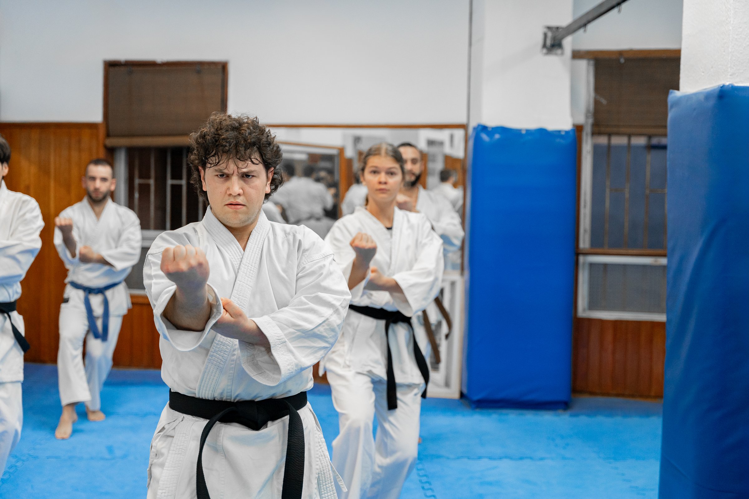 Group of karateka practicing fighting stances in a dojo, demonstrating discipline and focus