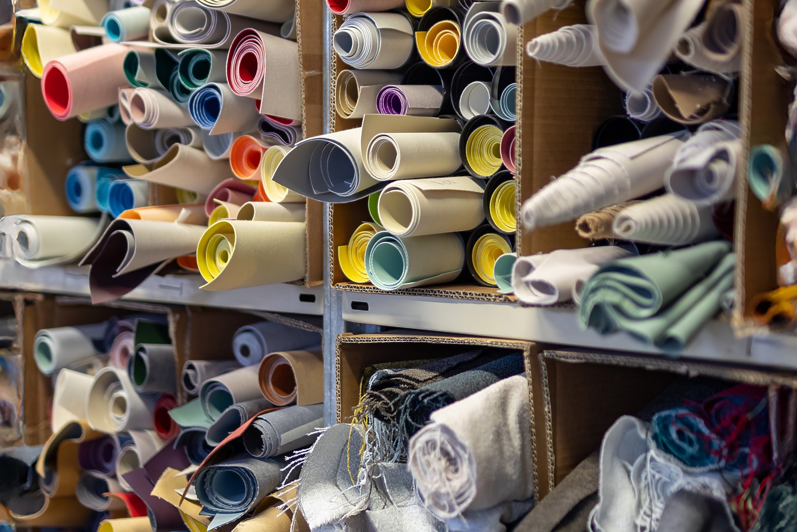 Interior of a textile warehouse or workshop, with numerous rolls of colorful fabric. A symbol of production, craftsmanship, tailoring, and the textile industry.