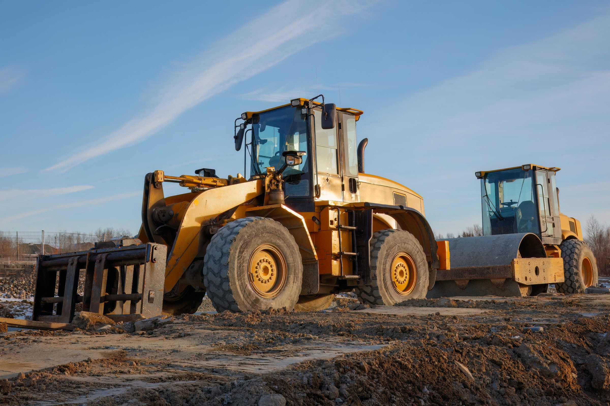Bulldozer and road roller on a construction site, showcasing heavy machinery for earthmoving, compacting, and paving during roadworks and infrastructure development.