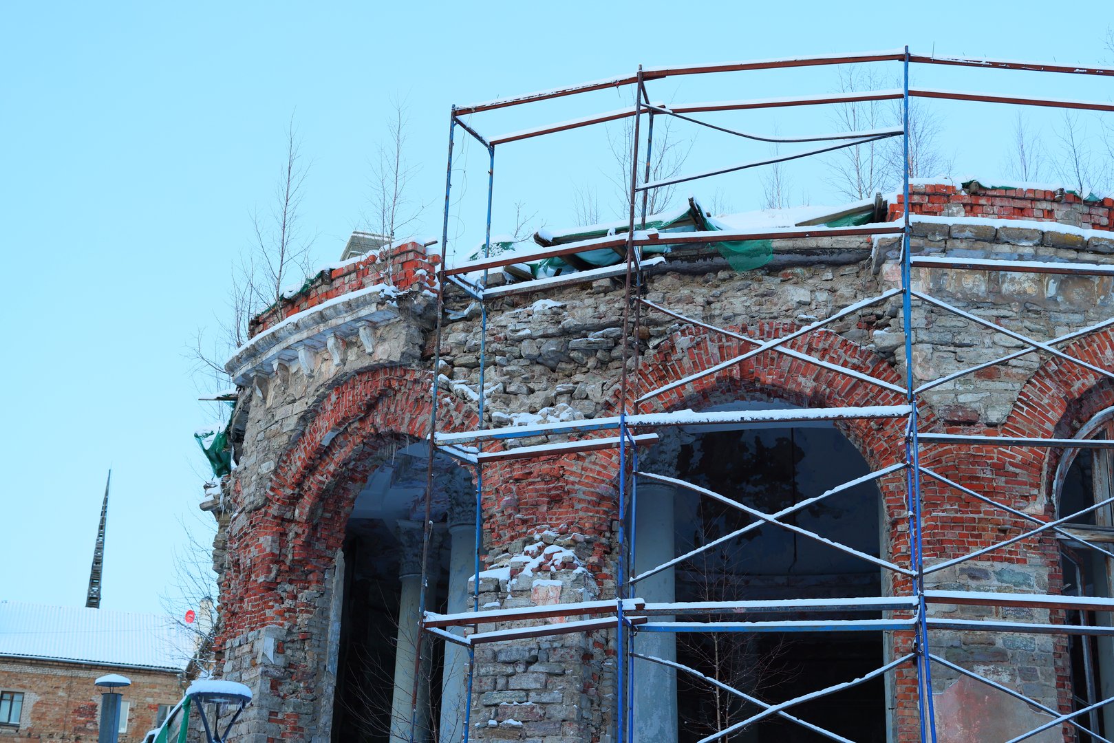 A historic brick building is undergoing extensive renovation, featuring visible scaffolding and exposed walls