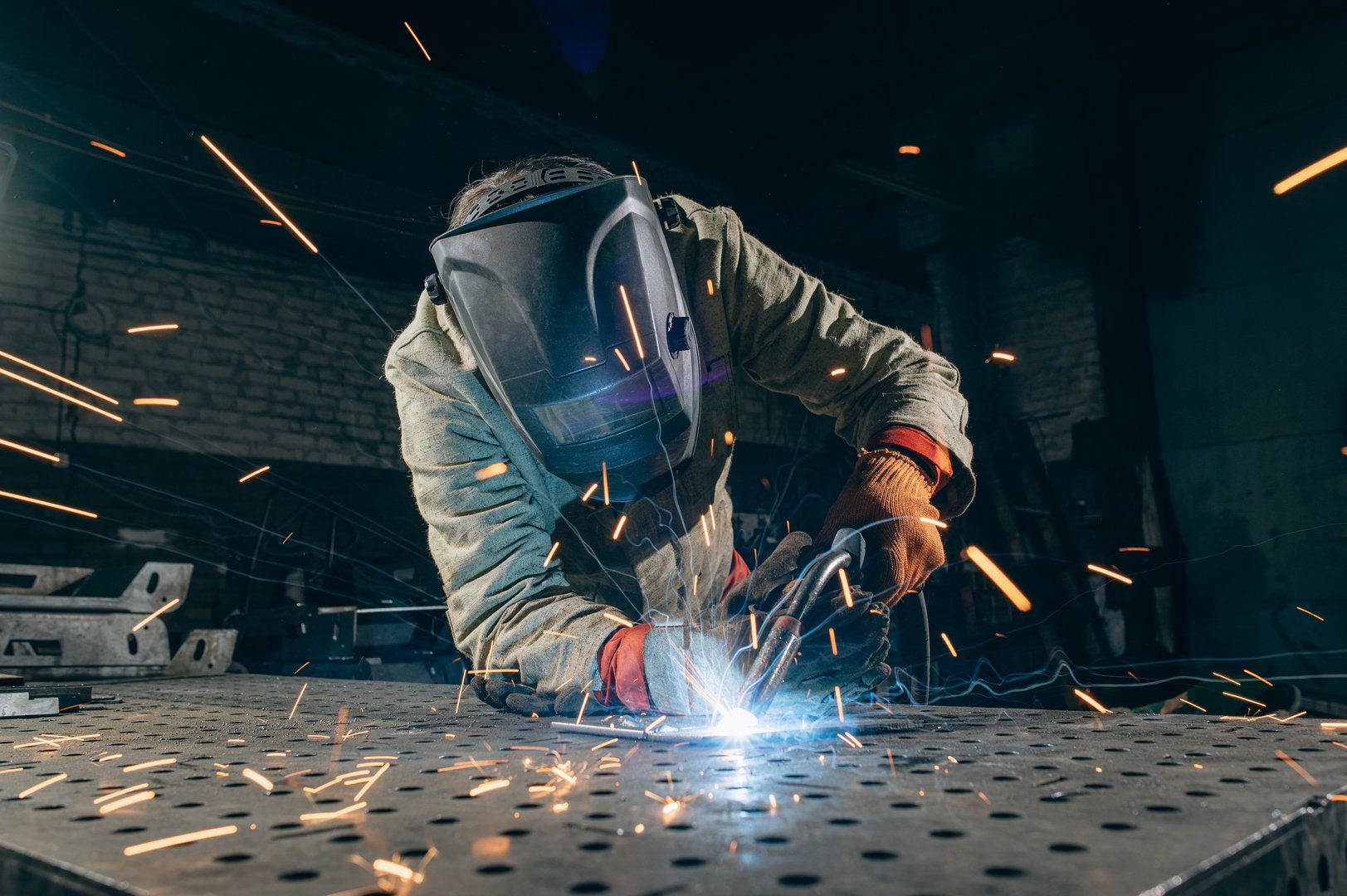 Professional metal worker welding in industrial workshop