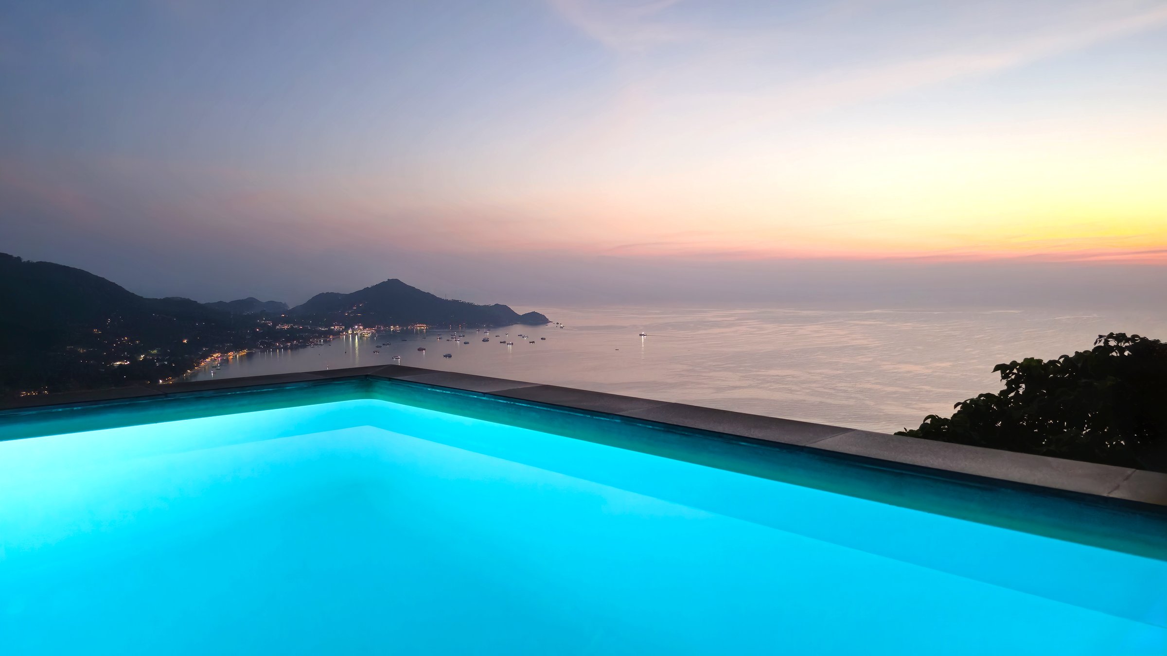 Infinity swimming pool overlooking tropical bay at sunset, Island Ko Tao, Surat Thani, Thailand, Southeast Asia. Infinity pool offering stunning panoramic views of a tropical bay at sunset, Island Ko Tao, Surat Thani, Thailand, Southeast Asia.