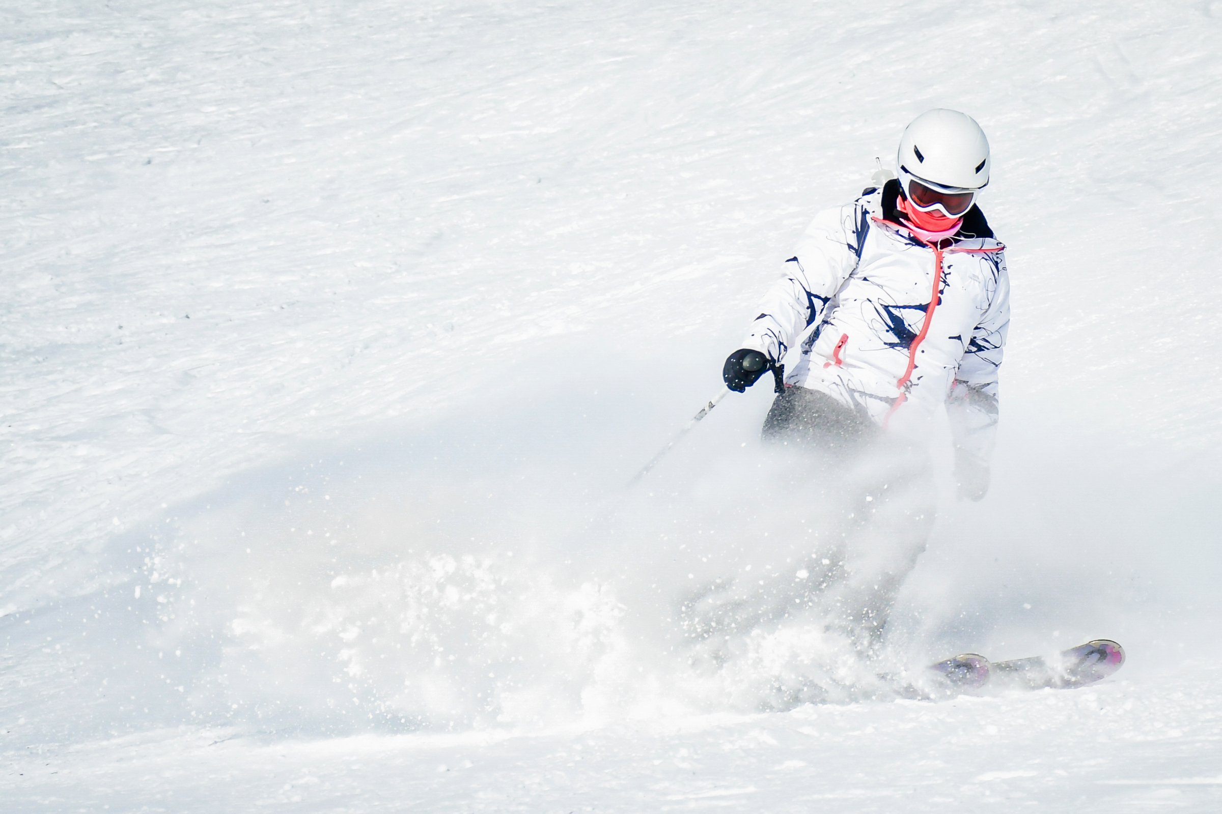 Woman Skier excited skiing downhill freeze fast motion on ski resort white slope pose carving in high alps mountains on sunny day. Ski resort with snow at winter