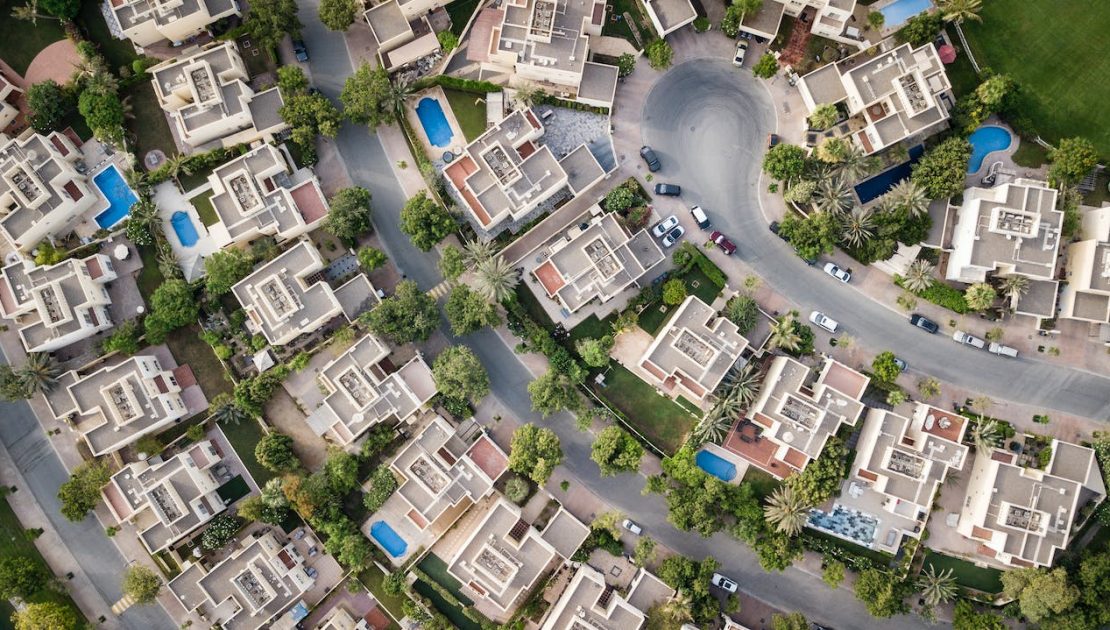 Aerial view of a suburban neighborhood with uniformly structured houses, gardens, and driveways, intersected by roads.