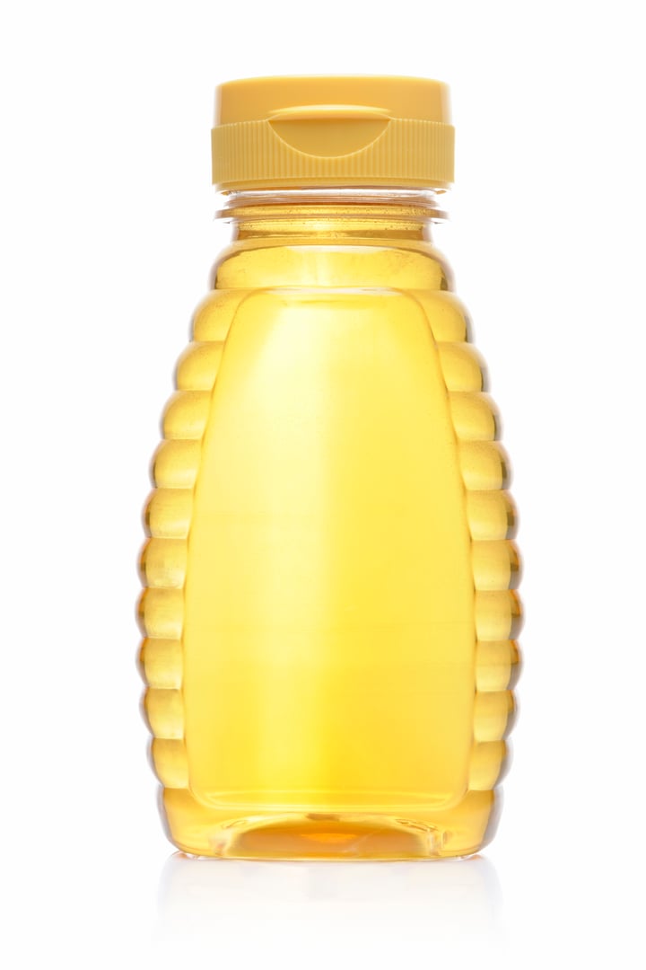 Bottle of golden honey isolated on white