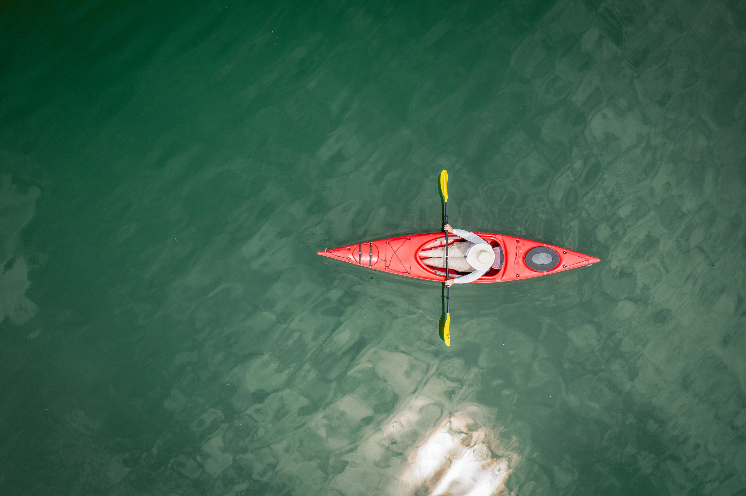 Top-down aerial view of a woman in a kayak on a lake