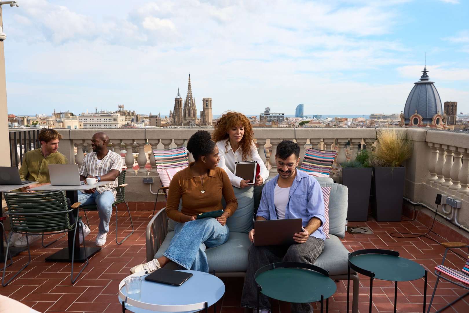 Young diverse business team working together with laptop computers on a sunny rooftop terrace overlooking the city