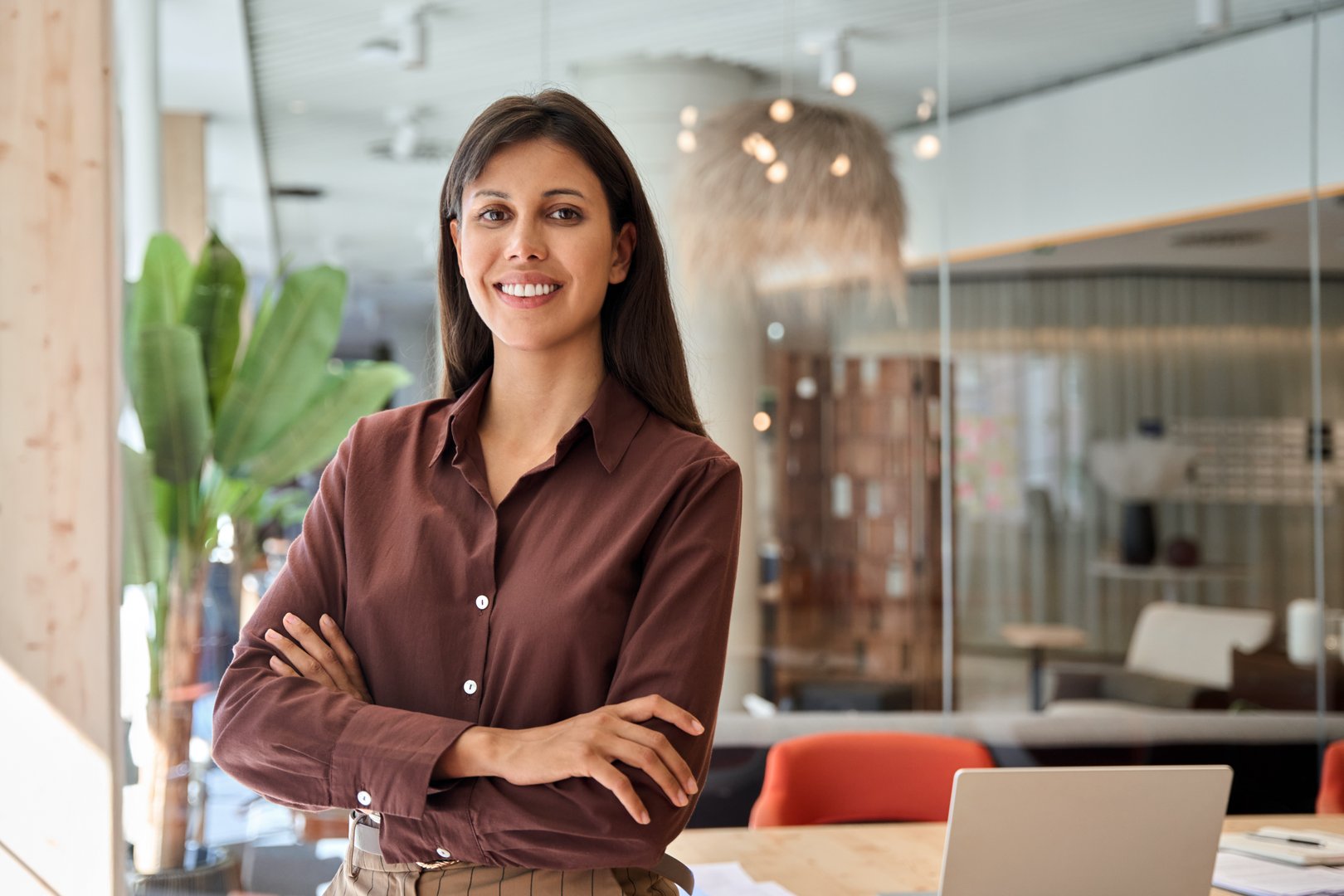 Beautiful hispanic young business woman with crossed arms smiling at camera