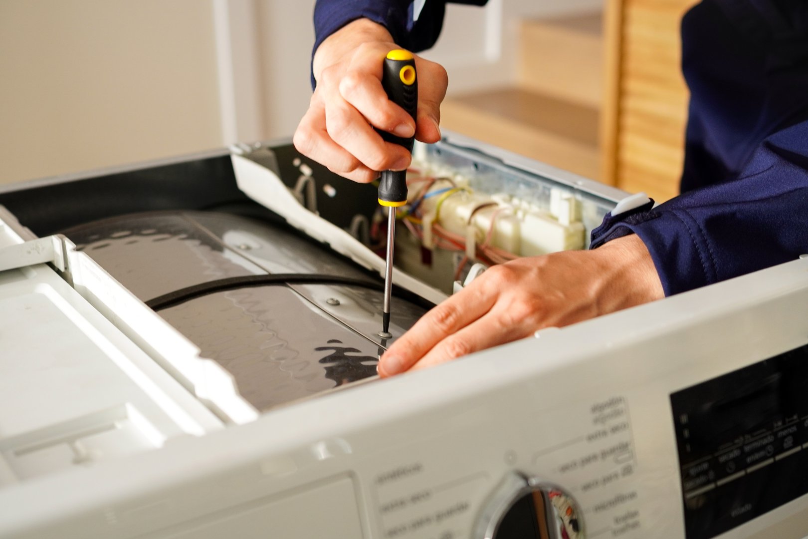 An appliance engineer repairing a broken washing machine