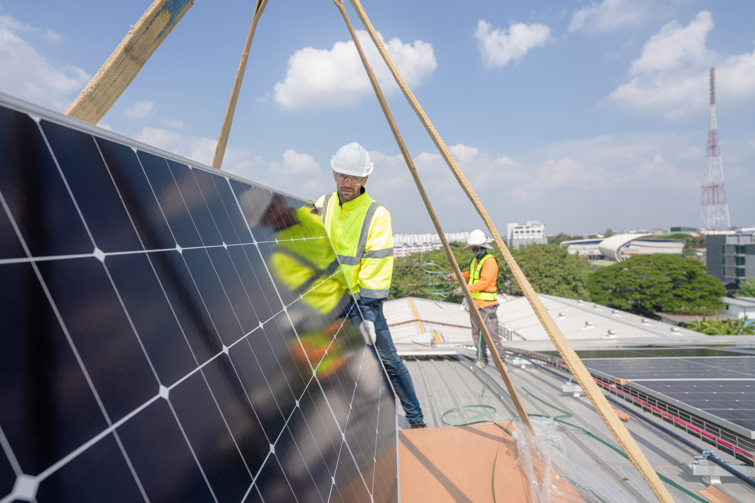 Men technicians carrying photovoltaic solar moduls on roof of factory on the morning. Installing a Solar Cell on a Roof. Solar panels on roof. Workers installing solar cell power plant eco technology.