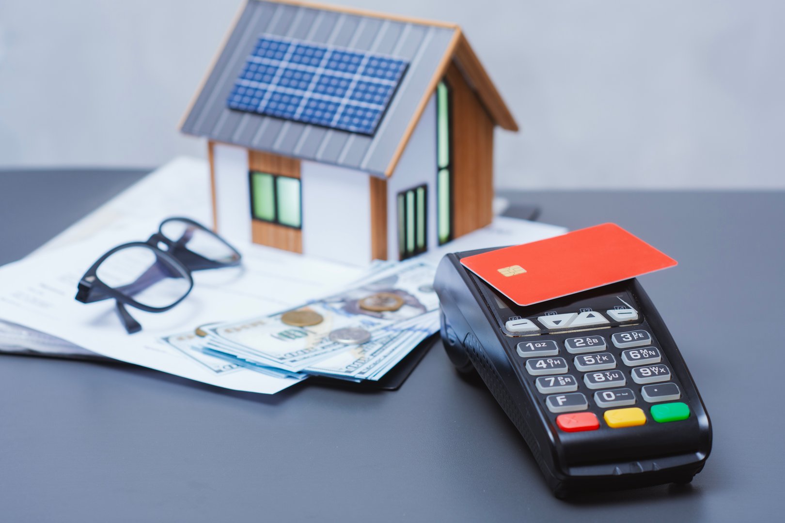 Payment terminal for credit card payment, US dollars and solar powered house model. Concept of property payment and real estate transactions for green housing