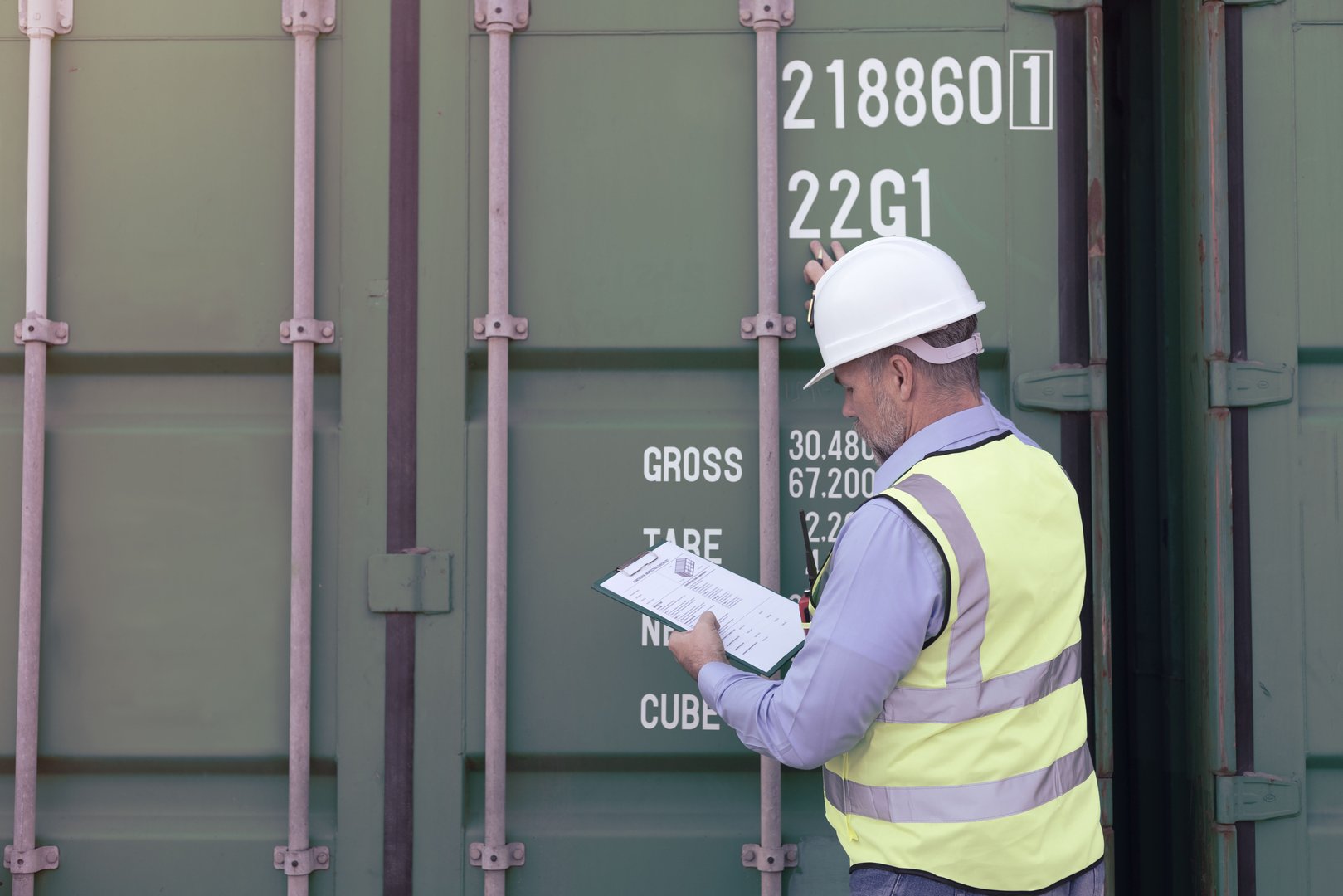 Foreman of logistic is checking document and inspection container. And wear safety uniform.