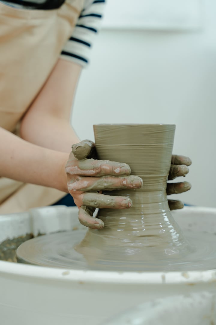 Hands shaping clay on a potter's wheel during a pottery class